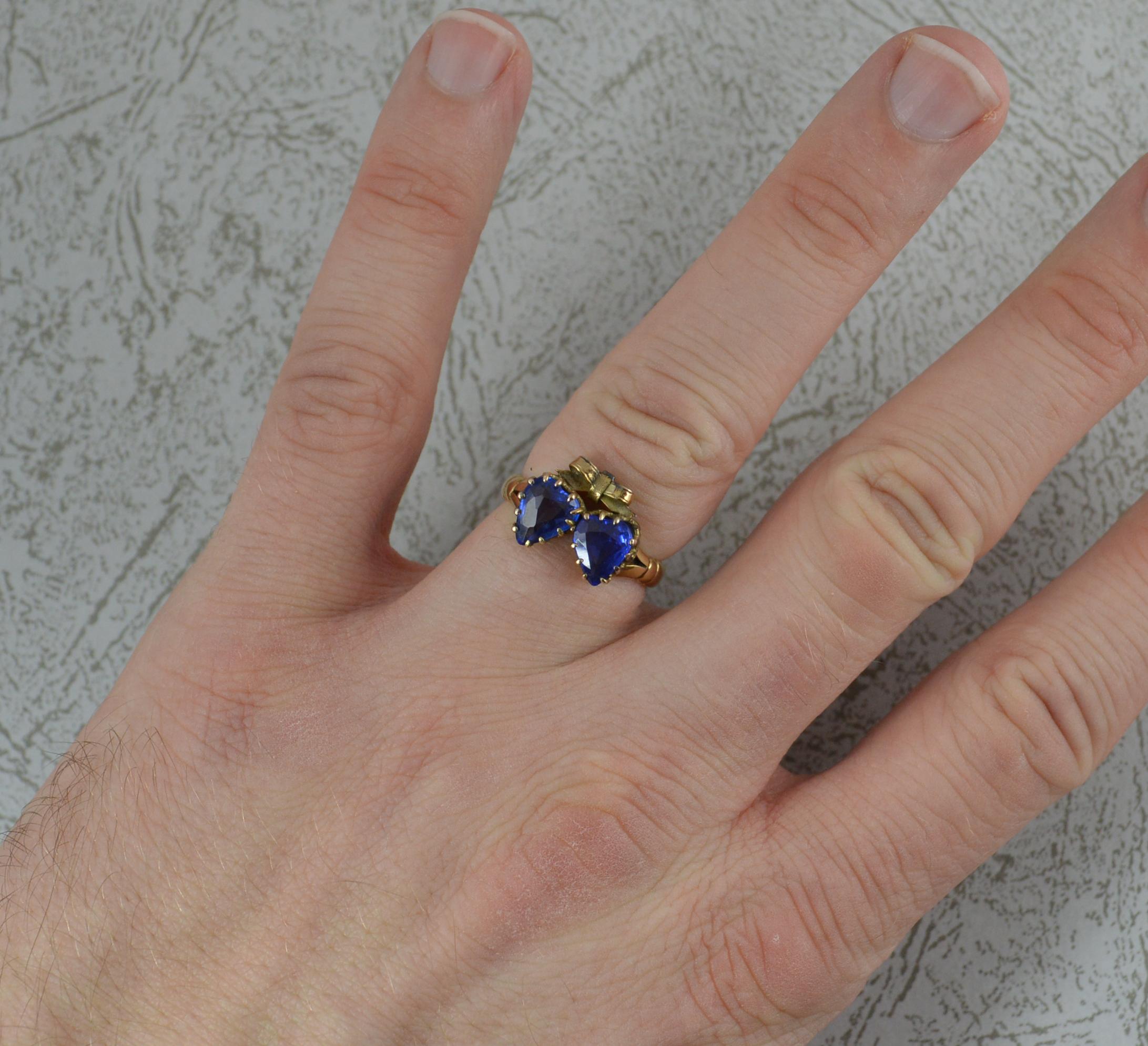 A beautiful two hearts ring from the late Victorian era.
Solid 9 carat gold example.
Designed as two hearts with bow above. The hearts cut vivid blue synthetic sapphires in multi claw settings.
Head approx 13mm x 10mm.


CONDITION ; Very good. Well