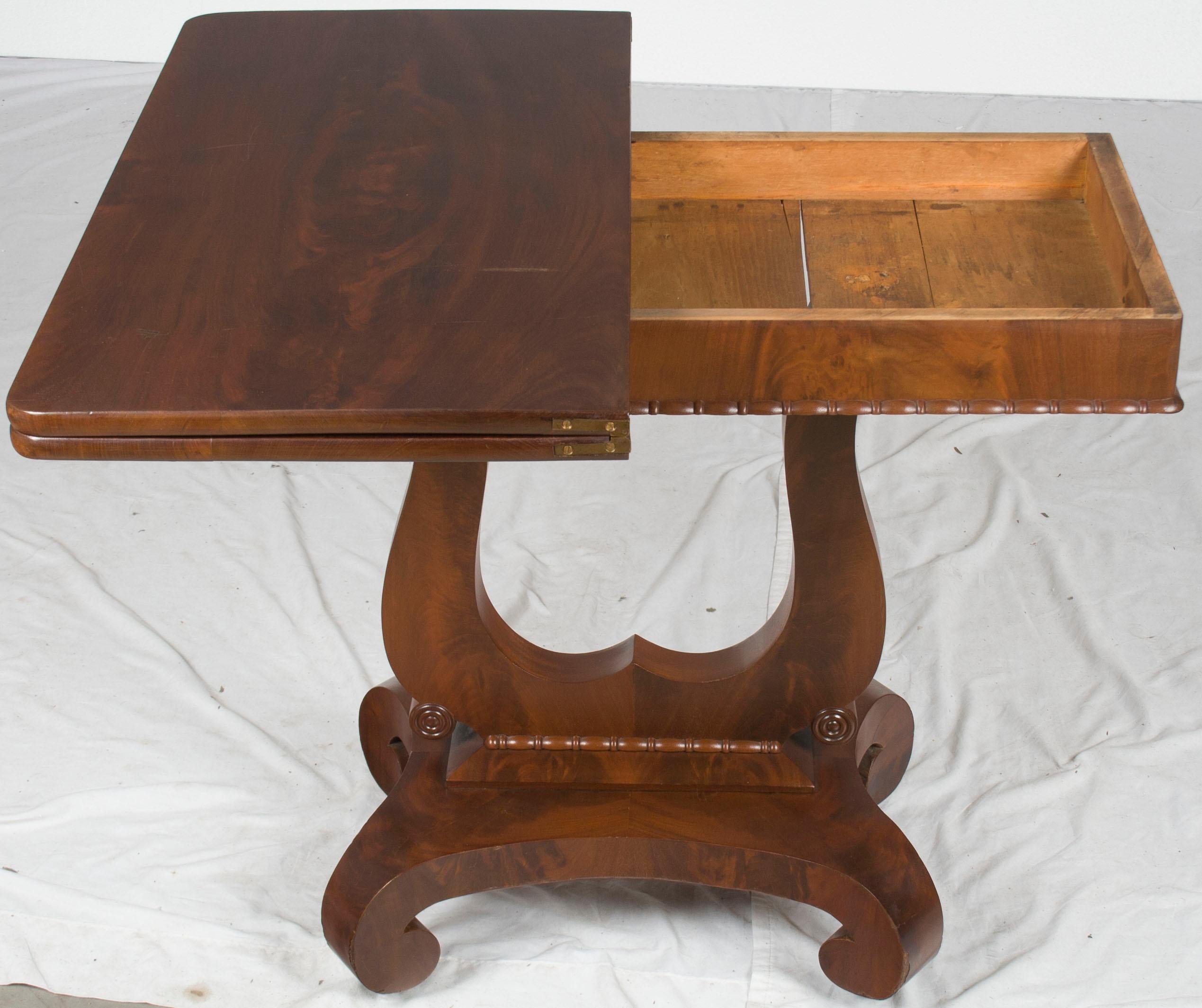 This classic antique flip top game table is from England and was made sometime around 1890. It is made from a lovely flame mahogany wood and remains in good condition today.

The main feature of this table is, of course, the flip top. While closed