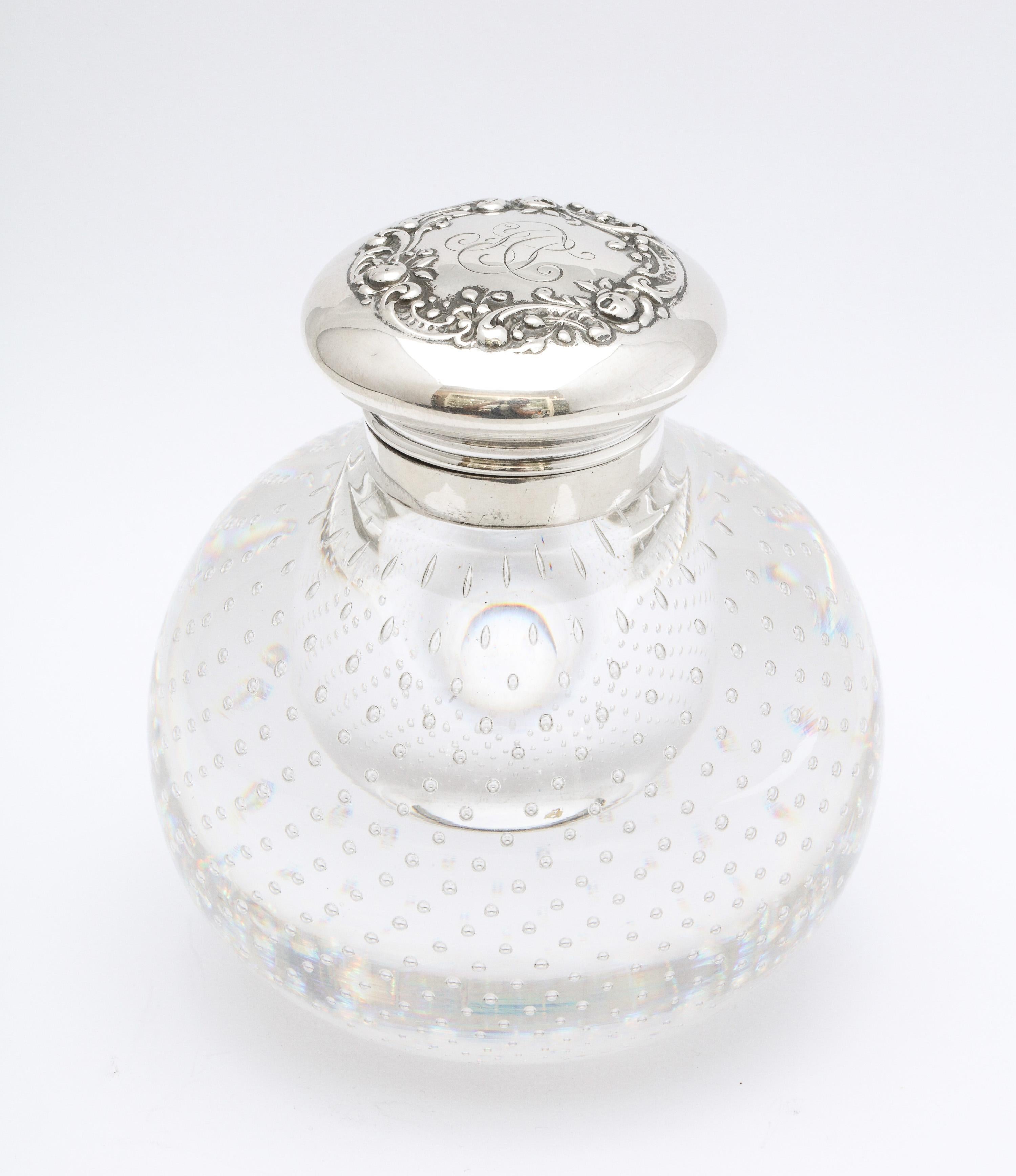 Victorian period, sterling silver-mounted controlled bubbles crystal inkwell with hinged lid, Gorham Mfg. Corp., Providence, Rhode Island, Ca. 1895. Interior of sterling silver hinged lid is lightly gilded; top of lid is decorated with flowers and