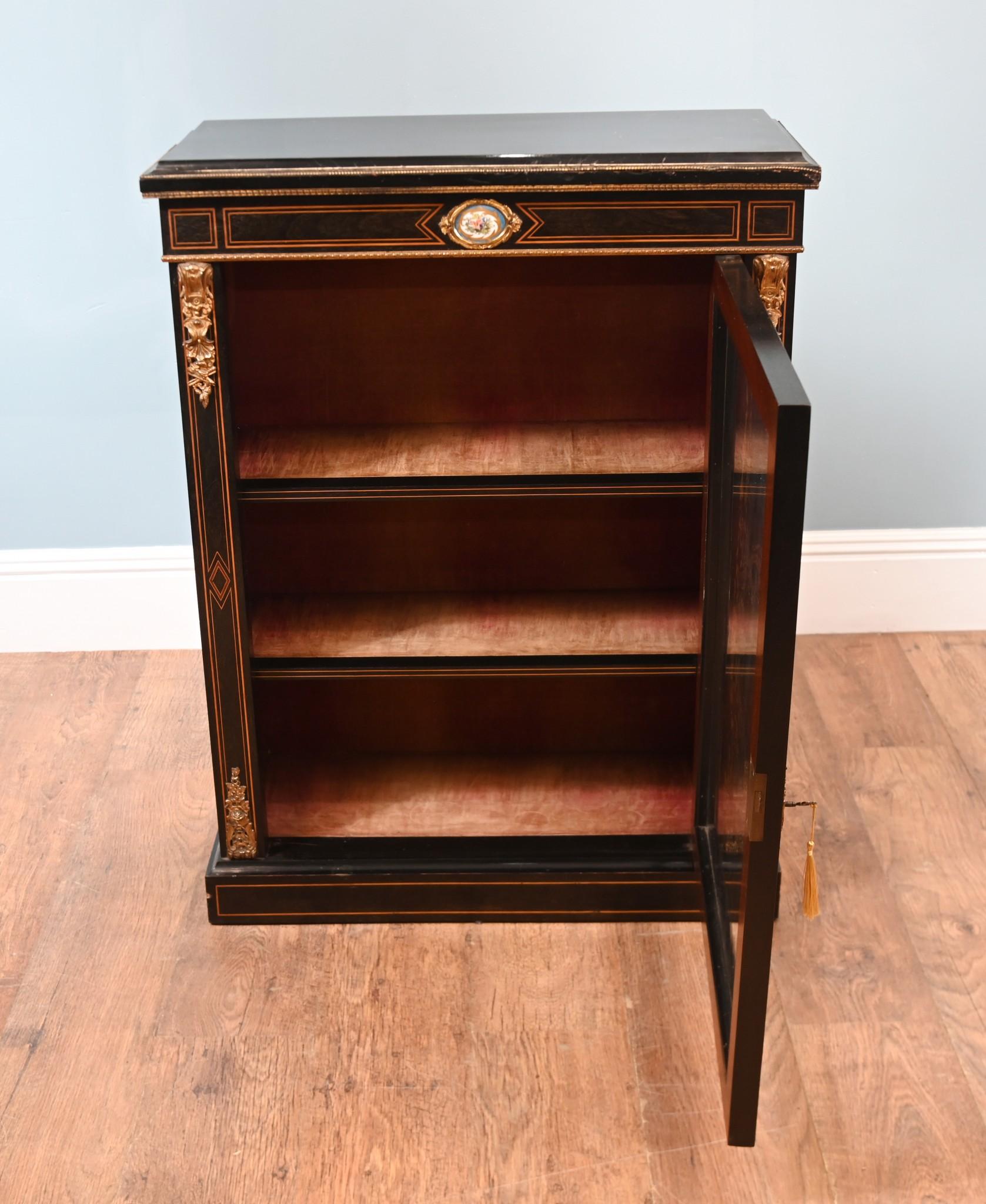 An ebonised pier cabinet with fine quality ormolu mounts in the French manner with a Sevres porcelain plaque mounting on the top freeze
Two adjustable shelves for books or china.
Ormolu mounts are original and finely cast
Features intricate boxwood