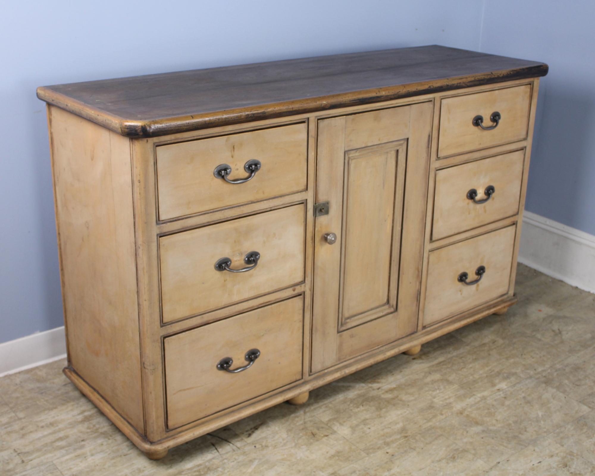 A highly versatile Victorian sideboard, cupboard or buffet. Original peach/beige paint has been rubbed back for a clean look. Wonderful thick pine top with good patina and mild interesting distress. Six deep roomy drawers and a center cupboard