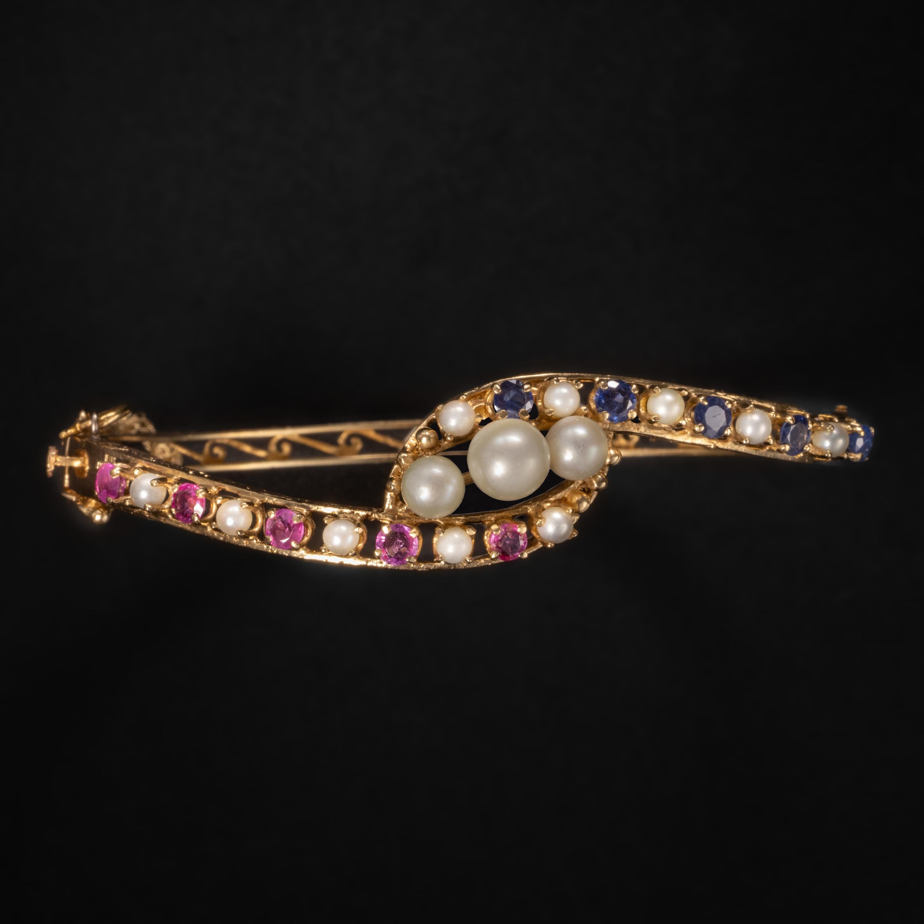 This Victorian pink & blue sapphire bangle with pearls was created in the late 1800s to early 1900s. It features 5 natural heated royal blue sapphires and five natural heated pink sapphires. Or rubies. There's enough red in these stones to