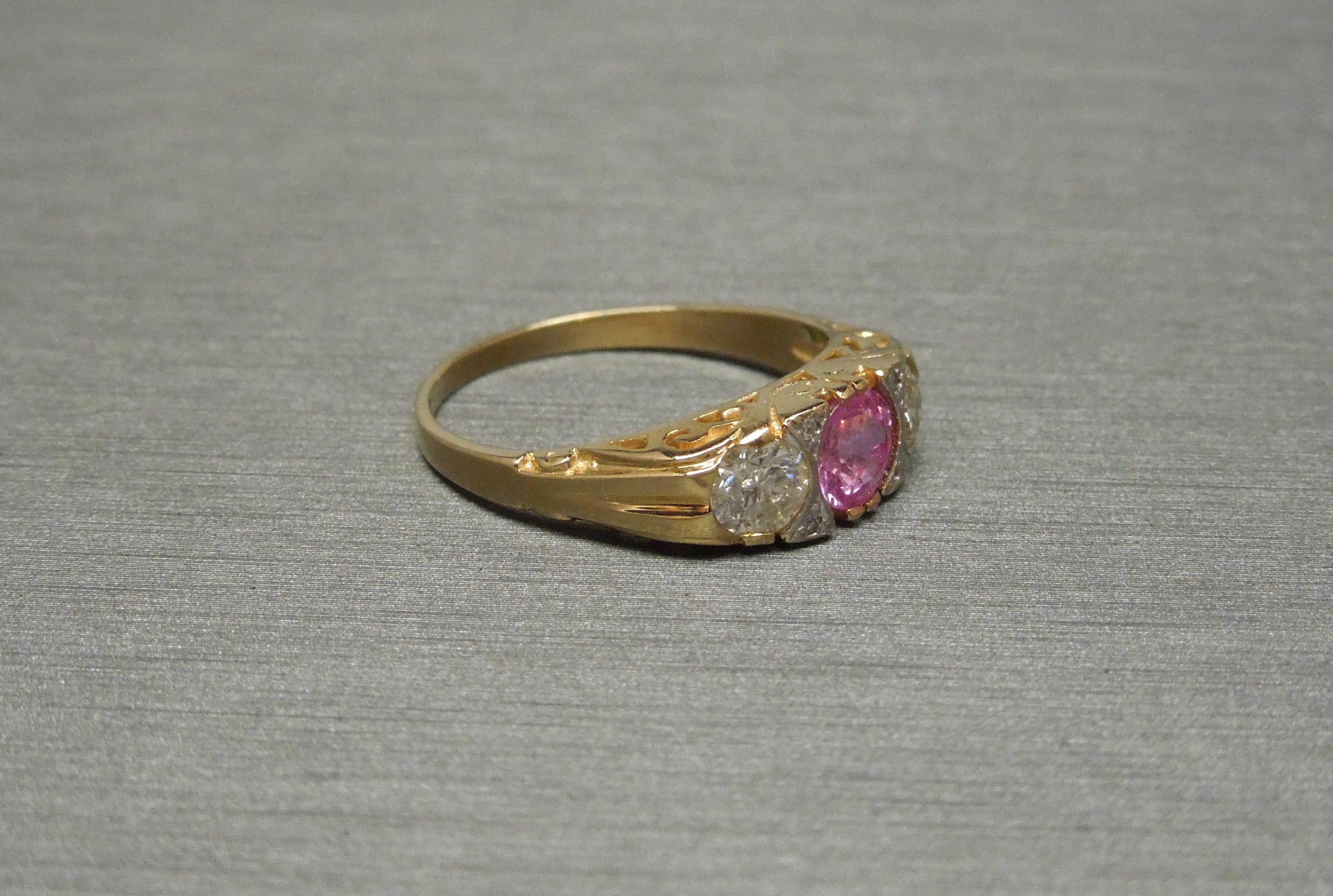 From a local New Orleans estate, this Victorian Pink Sapphire Trinity Ring features a central 0.68 carat Natural Intense Vivid Pink Sapphire at 4.7mm in diameter. Among the rarest colors of Sapphires in today's market, as well as Sapphire being the