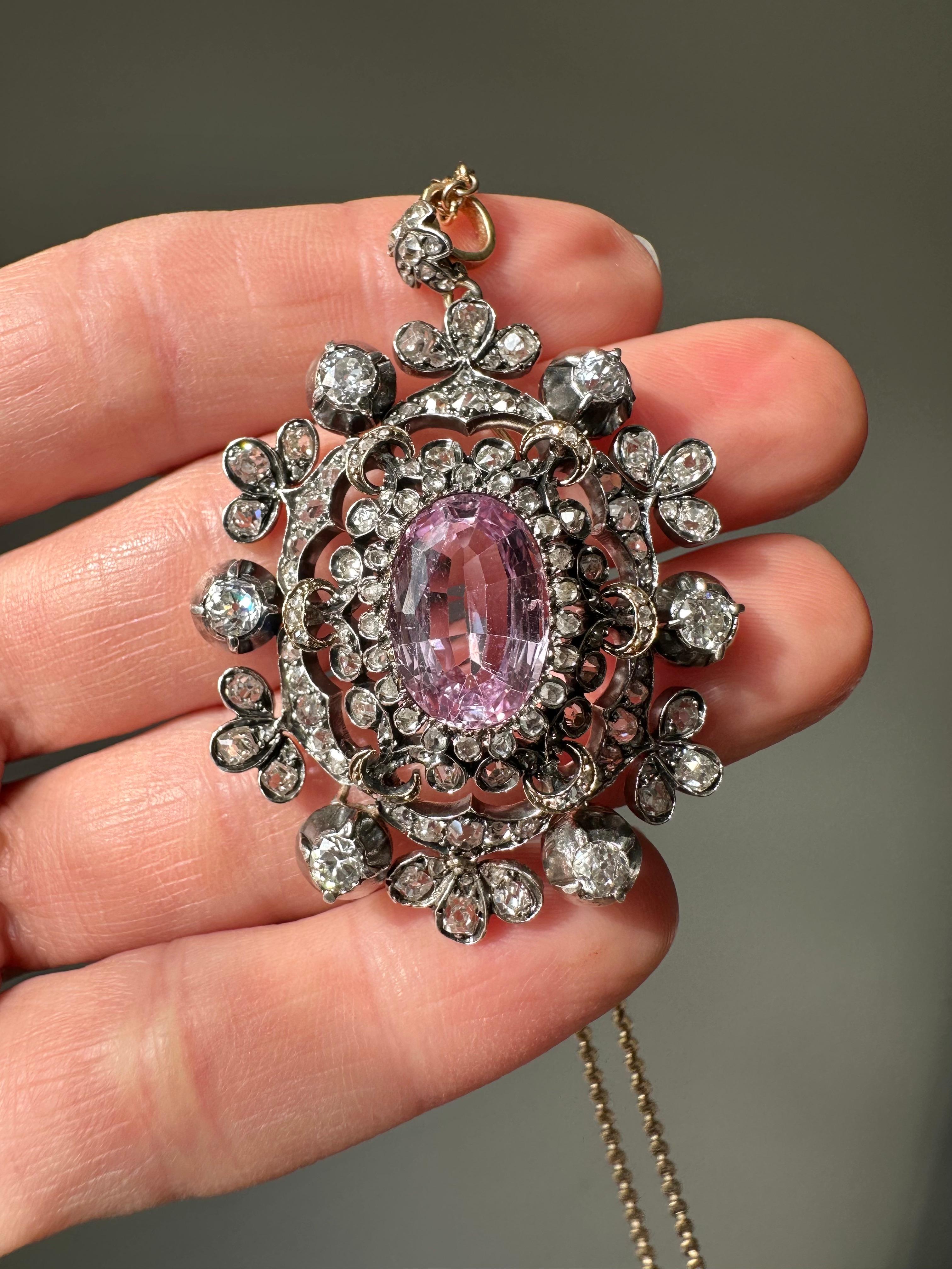 This gorgeous Victorian jewel centers on a 4.8 carat pastel pink topaz flower with glittering rose-cut diamond petals, wrapped in a fanciful frame of shimmering old mine and old single-cut diamonds. Intricately hand fabricated in silver over gold,