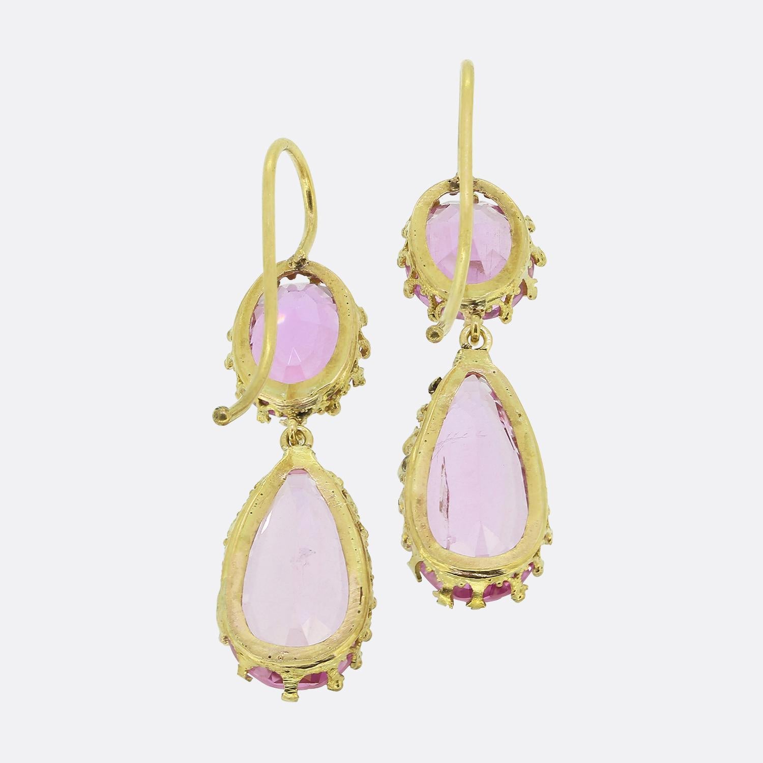 Here we have a charming pair of drop earrings taken from the Victorian period. Each 18ct yellow gold piece showcases two beautifully faceted pink topaz gemstones. The top stone is oval-shaped, while the bottom is pear shaped, both set in delicate