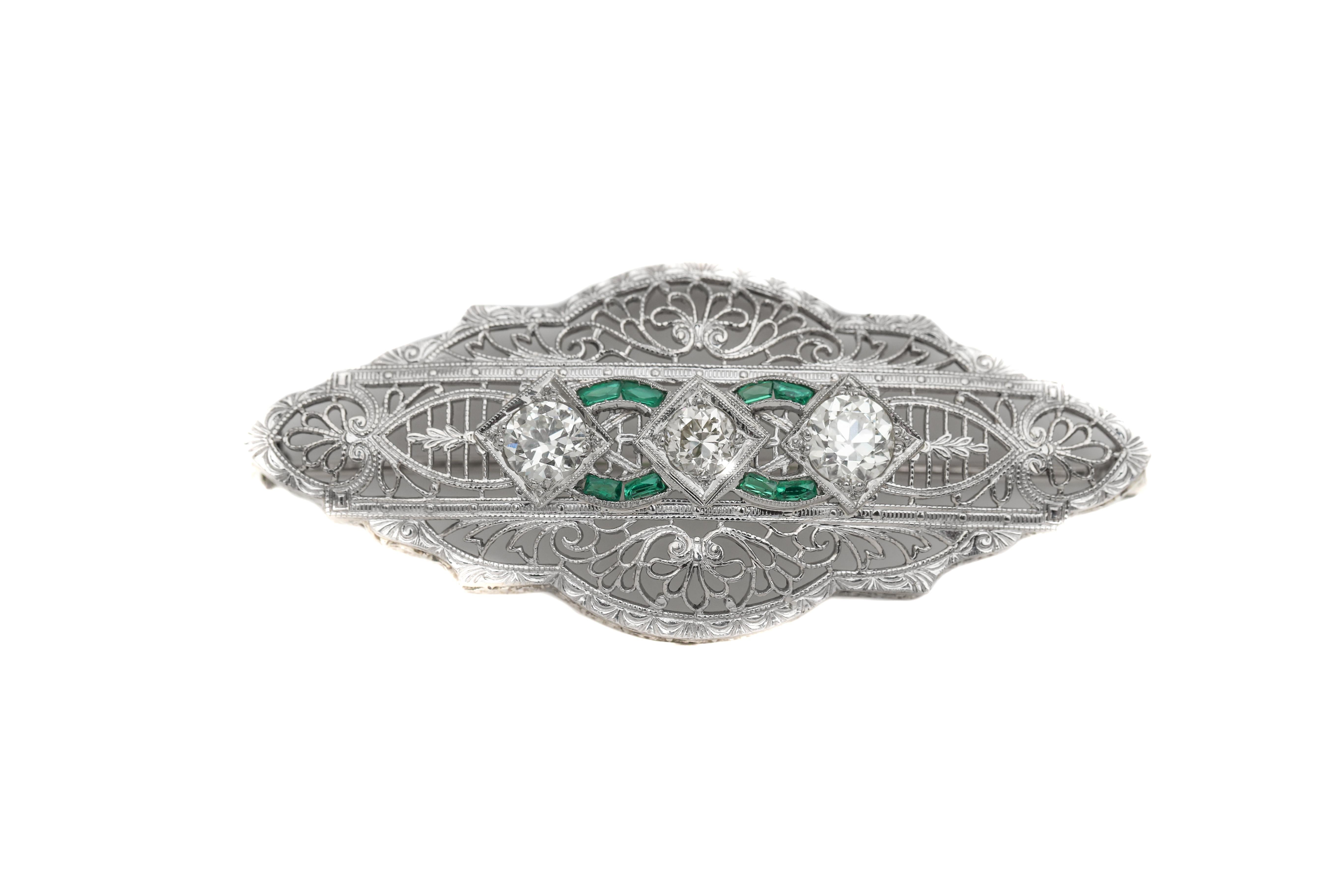 Description: 
This excellent victorian filigree brooch with a symmetrical design pattern featuring an emerald swirl on both sides of the diamond centers. Total carat weight tis 1.20 carats and H color and VS clarity is the average grade. 

This is a