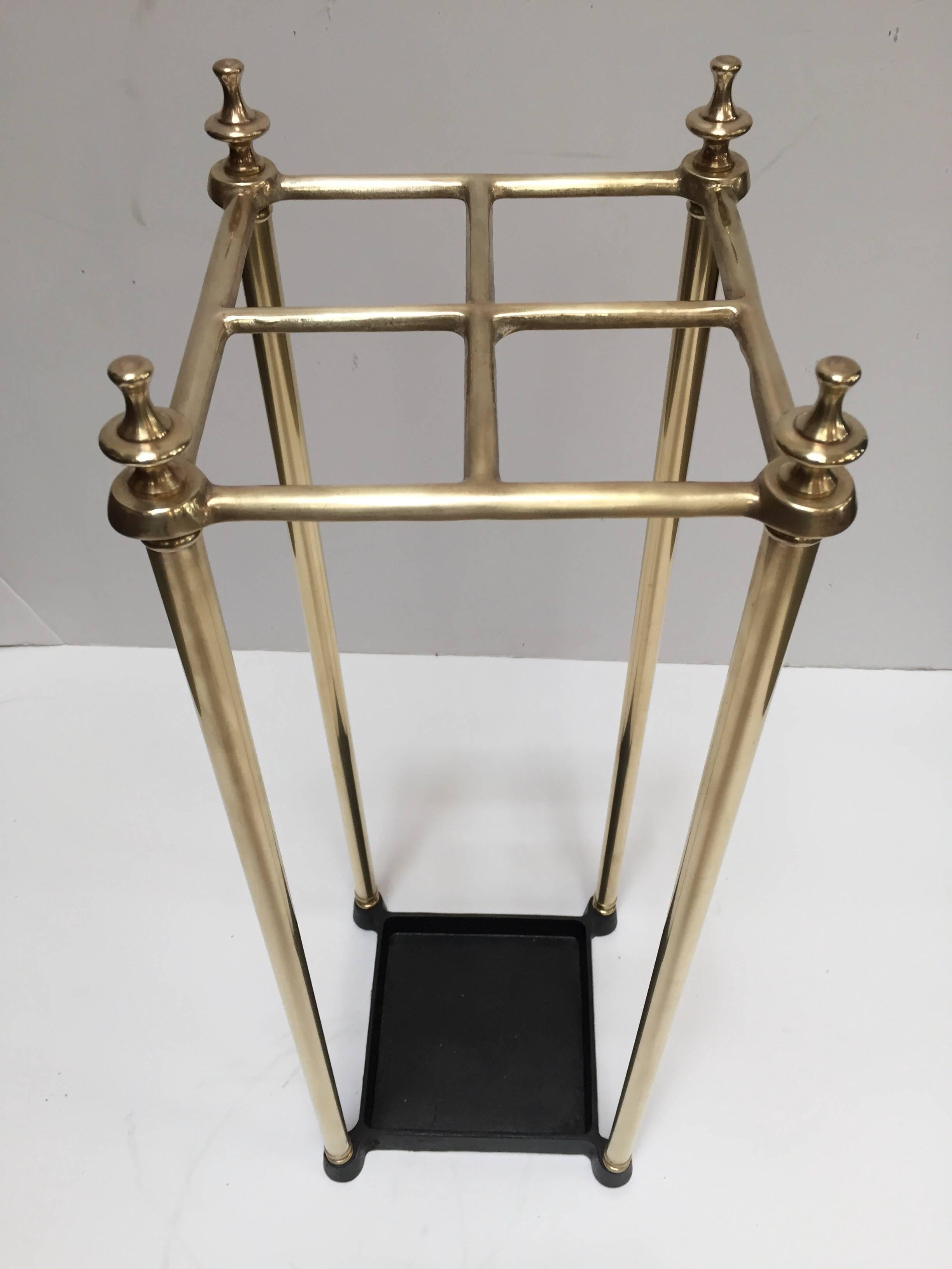 Victorian brass umbrella stand or stick stand.
Polished brass top divided into four sections to hold either walking sticks or umbrellas.
Square umbrella brass valet rack with four sections and black iron tray and supported upon a tubular frame