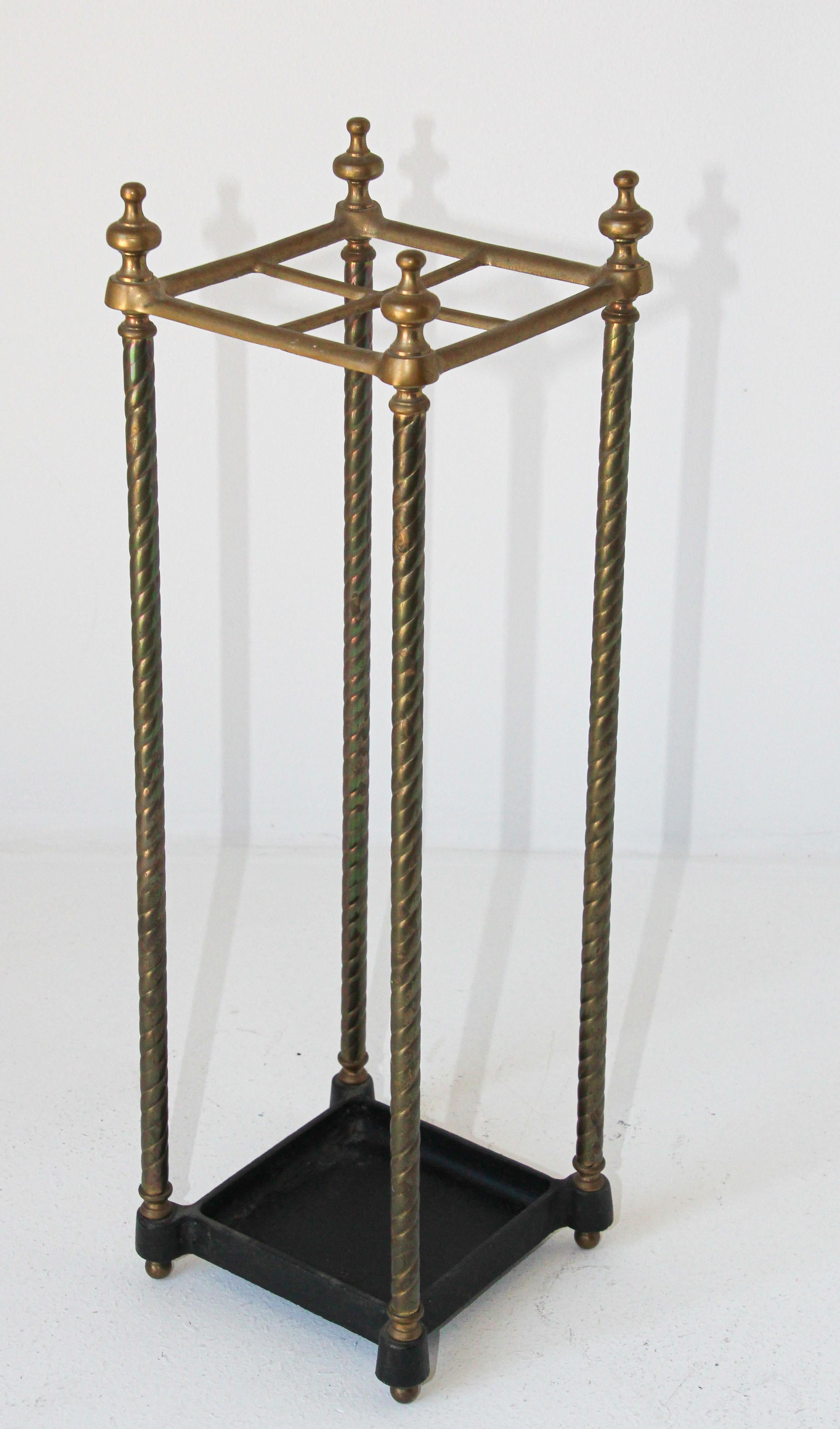 Victorian brass umbrella stand or stick stand.
Vintage polished brass top divided into four sections to hold either walking sticks or umbrellas.
Square umbrella brass valet rack with four sections and black iron tray and supported upon a tubular