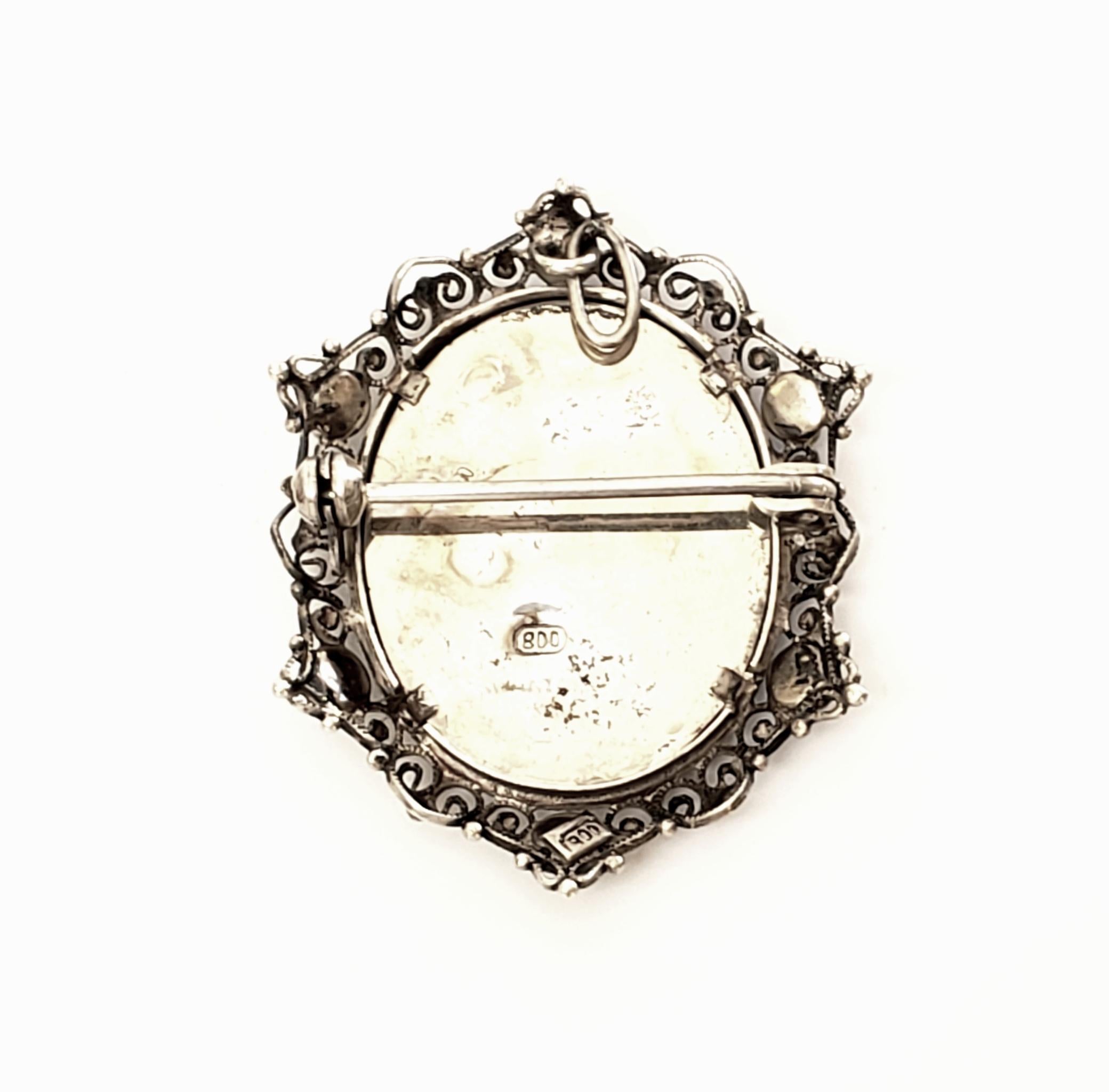 800 silver and blue bead portrait pin and pendant.

This beautiful piece can be worn as a pin or a pendant, features a hand painted lady's portrait in a 800 silver filigree frame with small blue beads.

Measures 1 1/2