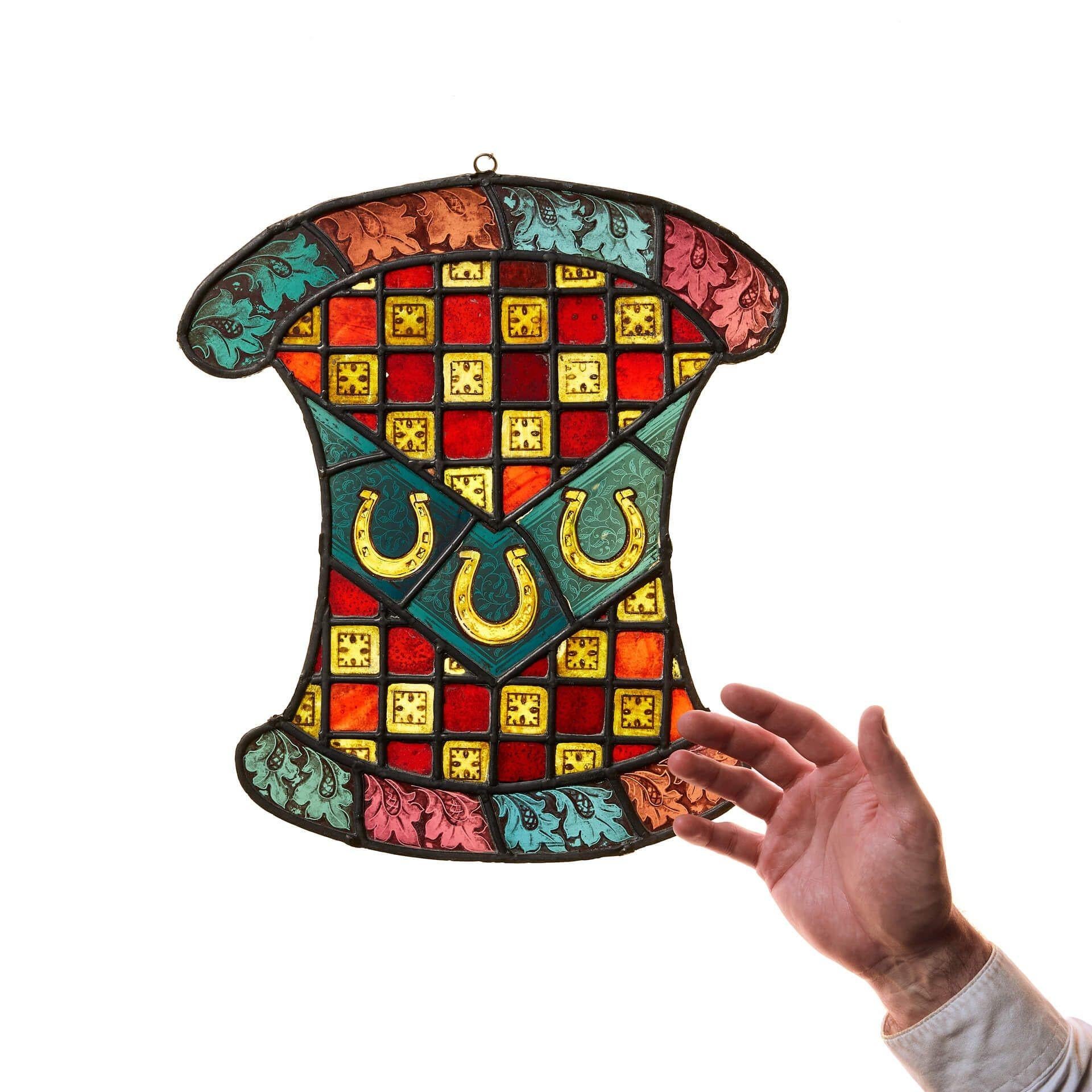 Un vibrant vitrail victorien suspendu sous la forme d'un pseudo-armorial.

De forme inhabituelle, ce petit panneau de vitrail utilise une myriade de vitres et de motifs de couleurs différentes qui ne manqueront pas d'attirer l'attention. Un damier
