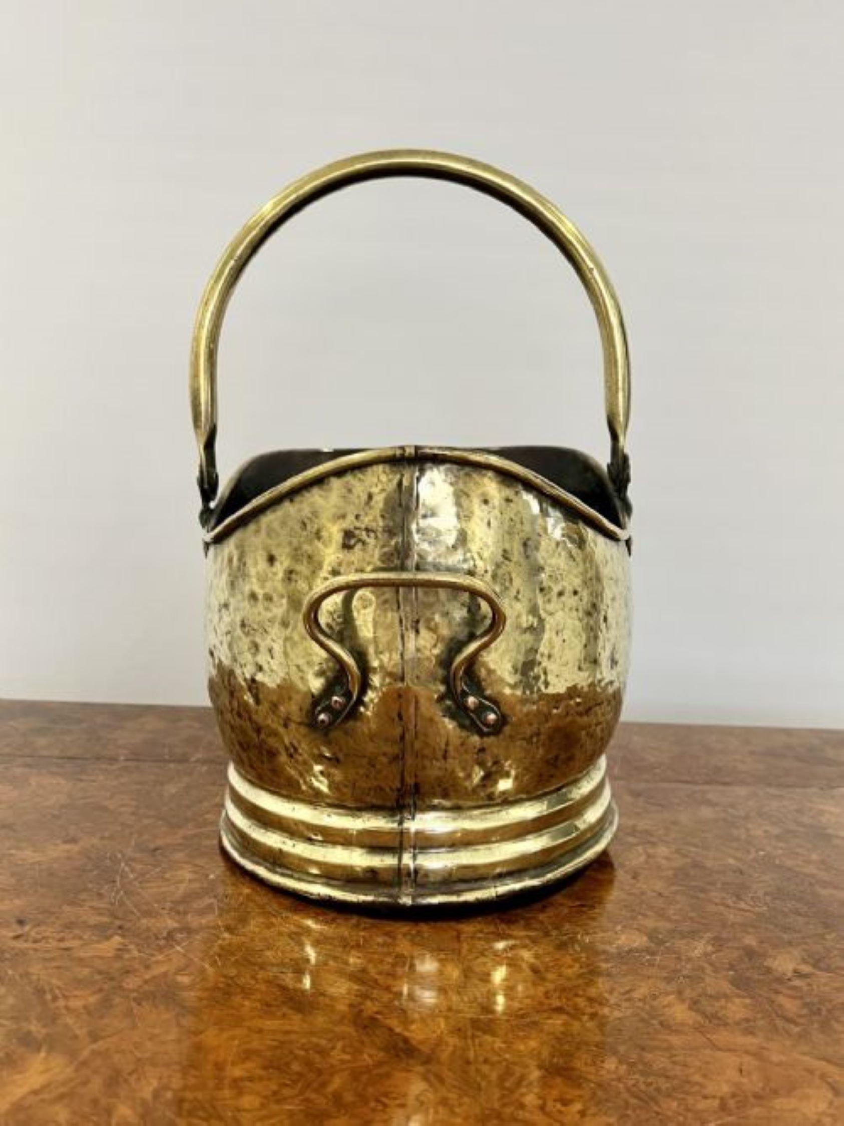 Antique Victorian quality brass helmet coal scuttle having a shaped carrying handle with a shaped quality brass helmet coal scuttle 