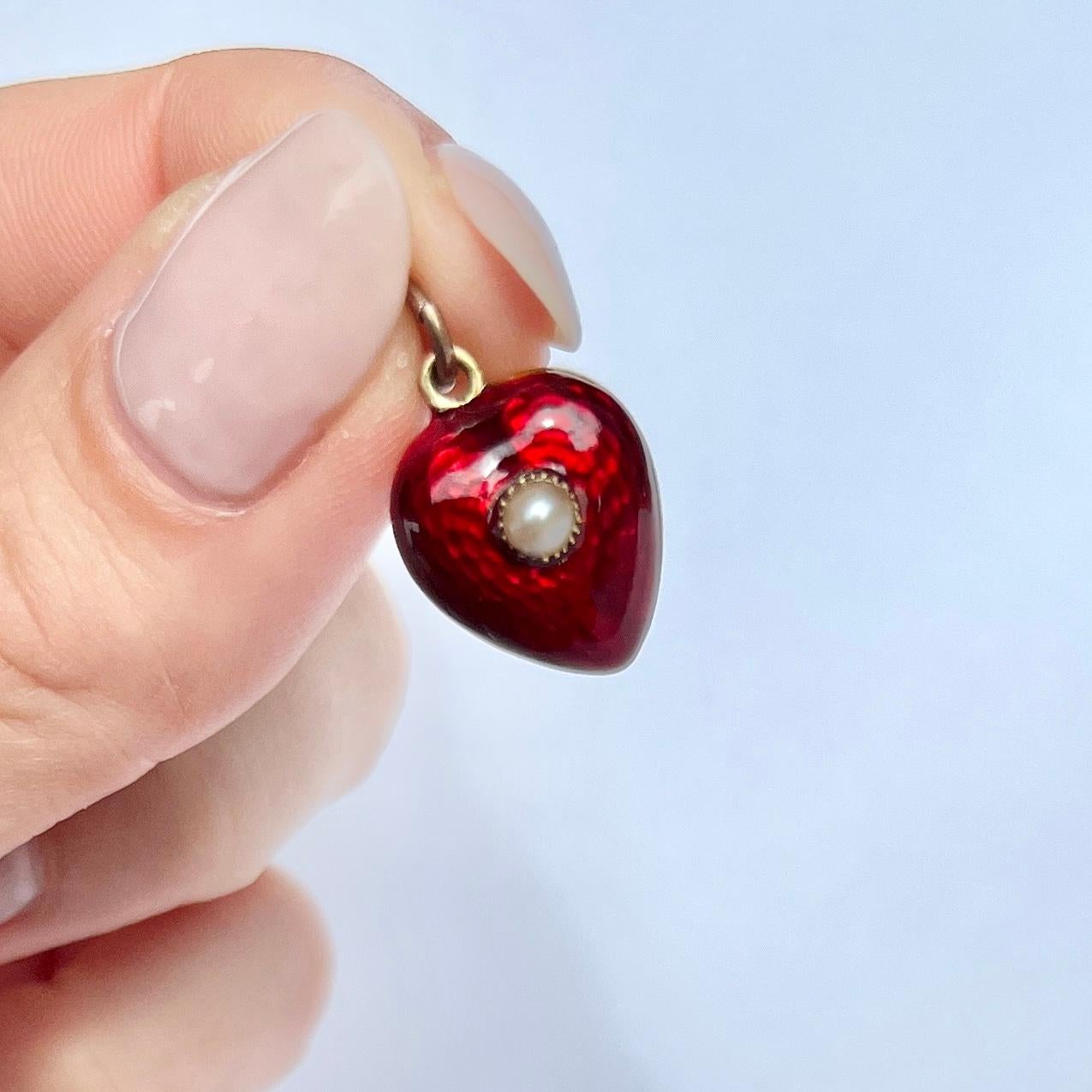 The enamel on this pendant is striking red and has a lovely shimmer to it. At the centre of the heart there is a sweet pearl. The pendant has a locket back and holds a lock of hair. 

Dimensions: 15x14mm

Weight: 2.5g