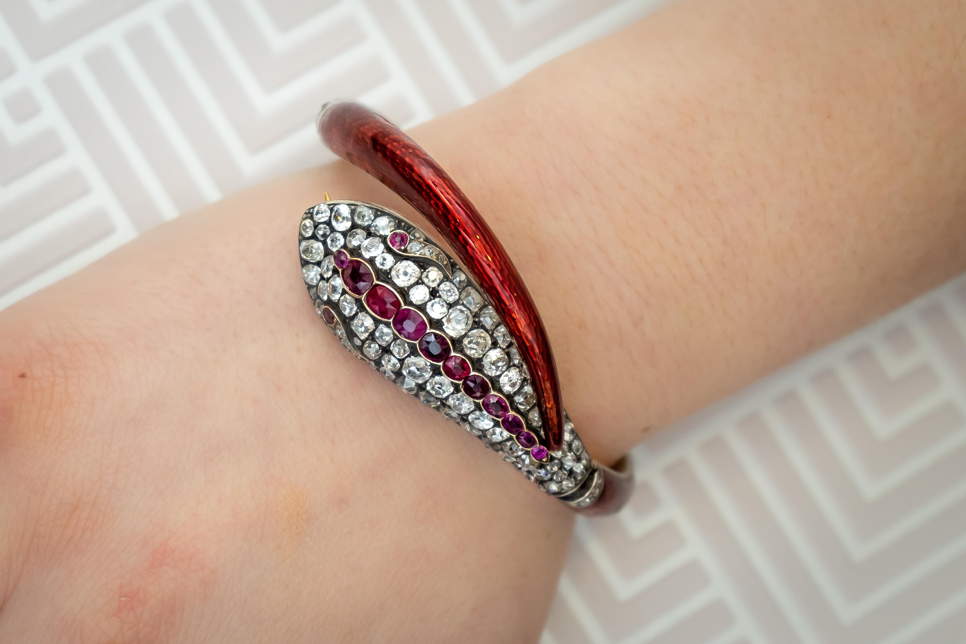 A Victorian red guilloche enamel snake bangle, the head is set with old-cut diamonds and mixed-cut rubies, with a red guilloche enamelled body and tail, with diamond details on the three hinges, circa 1860.
