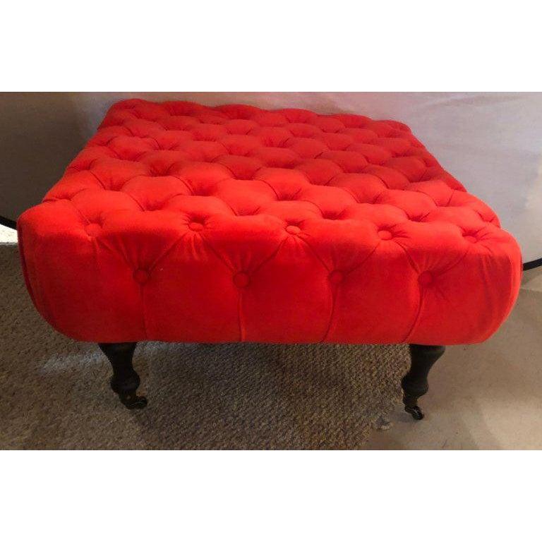 A Victorian square window bench or ottoman. This fine hand-tufted ottoman is simply stunning while sitting on a Victorian feet having brass casters and sabots. The ottoman features a glamourous fire-engine red color and intricate wood crafted legs.