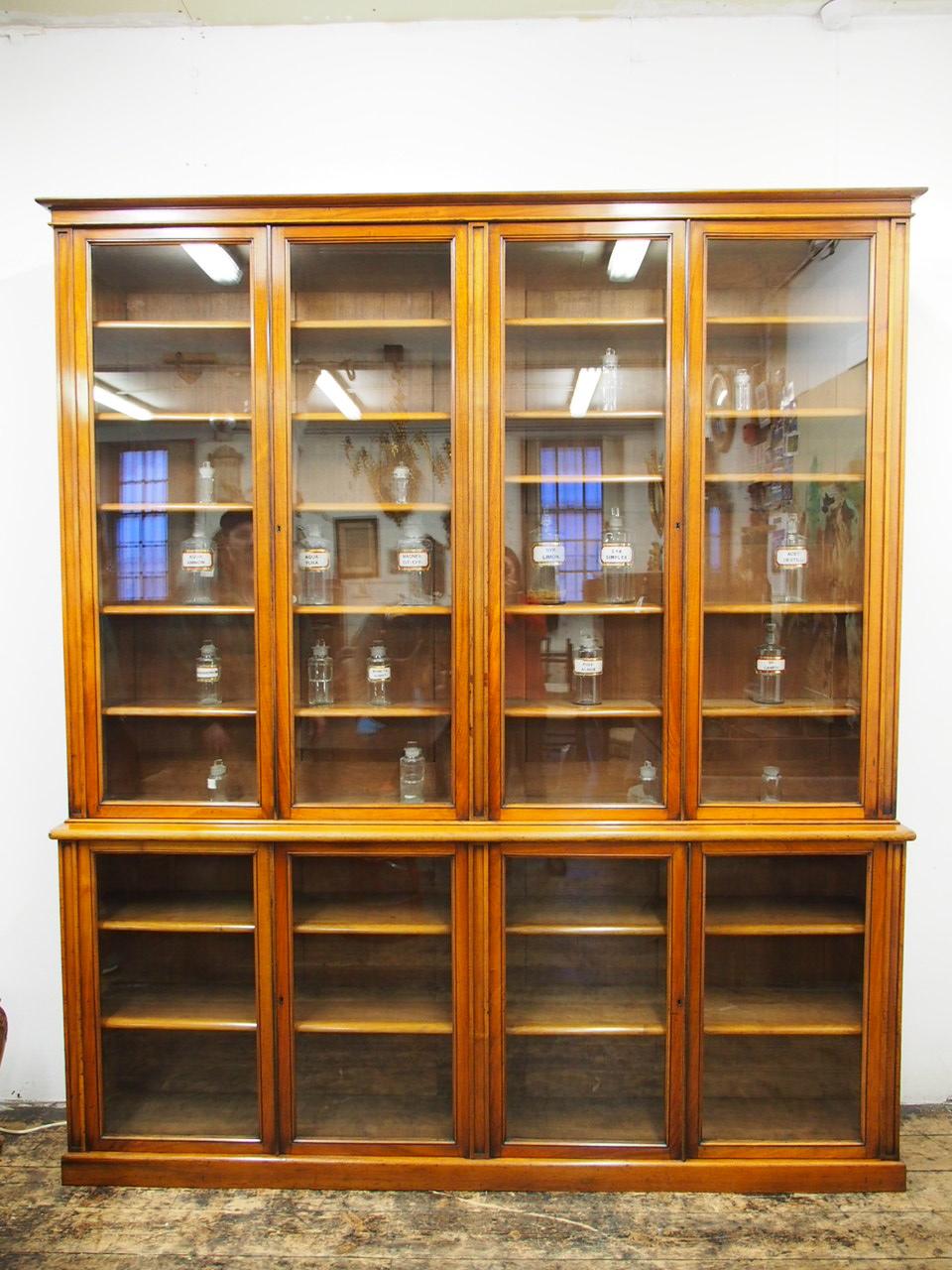 Four-door red walnut cabinet bookcase or display cabinet, circa 1880. With a simple moulded cornice above a shallow apron that sits beneath above four glazed doors, all hanging in pairs. There are simple pilasters dividing the doors, which continues