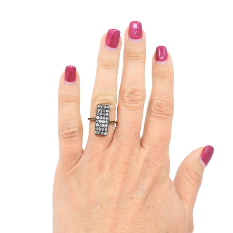 Un anello di diamanti in stile vittoriano in oro 14k.
Questo anello rettangolare unisce il fascino del vecchio mondo a un design strutturato. La fascia d'oro ha una tonalità calda che contrasta con l'incastonatura scura, che si è ossidata nel corso