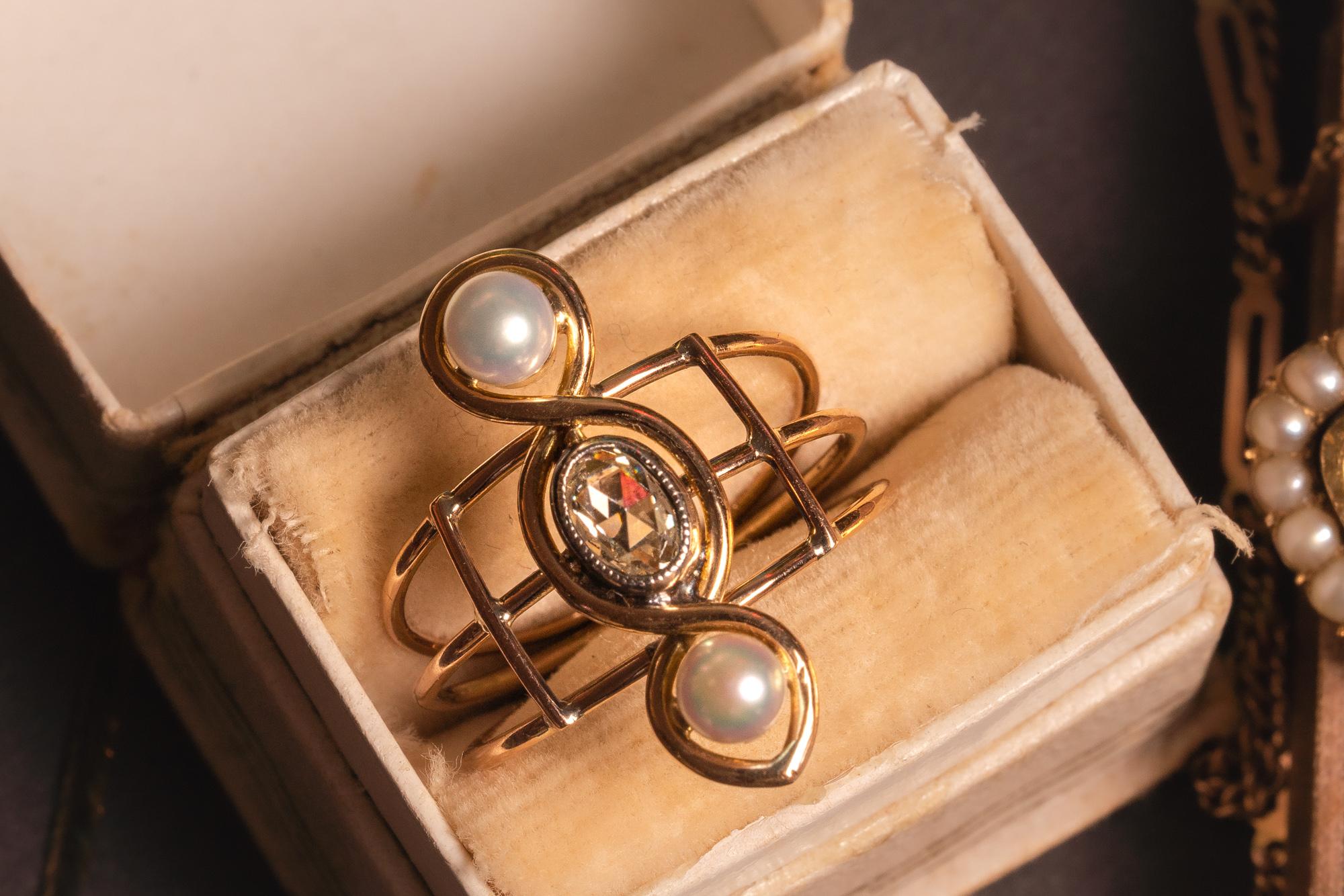A very unusual Victorian revival three-stones ring, featuring two snow-white pearls and a chunky oval rose cut diamond of circa 0.8 ct.

The diamond measures 5.5 x 4 mm and is set in an eternity-shaped setting with two lovely pearls. The shank is