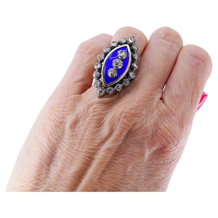 A gorgeous Victorian ring, made of silver and 18k gold, features enamel and diamond.
The ring has striking design owing to its elliptic shape and the bright blue enamel in the center. The diamonds are rose cut, bezel set in silver. Three diamonds