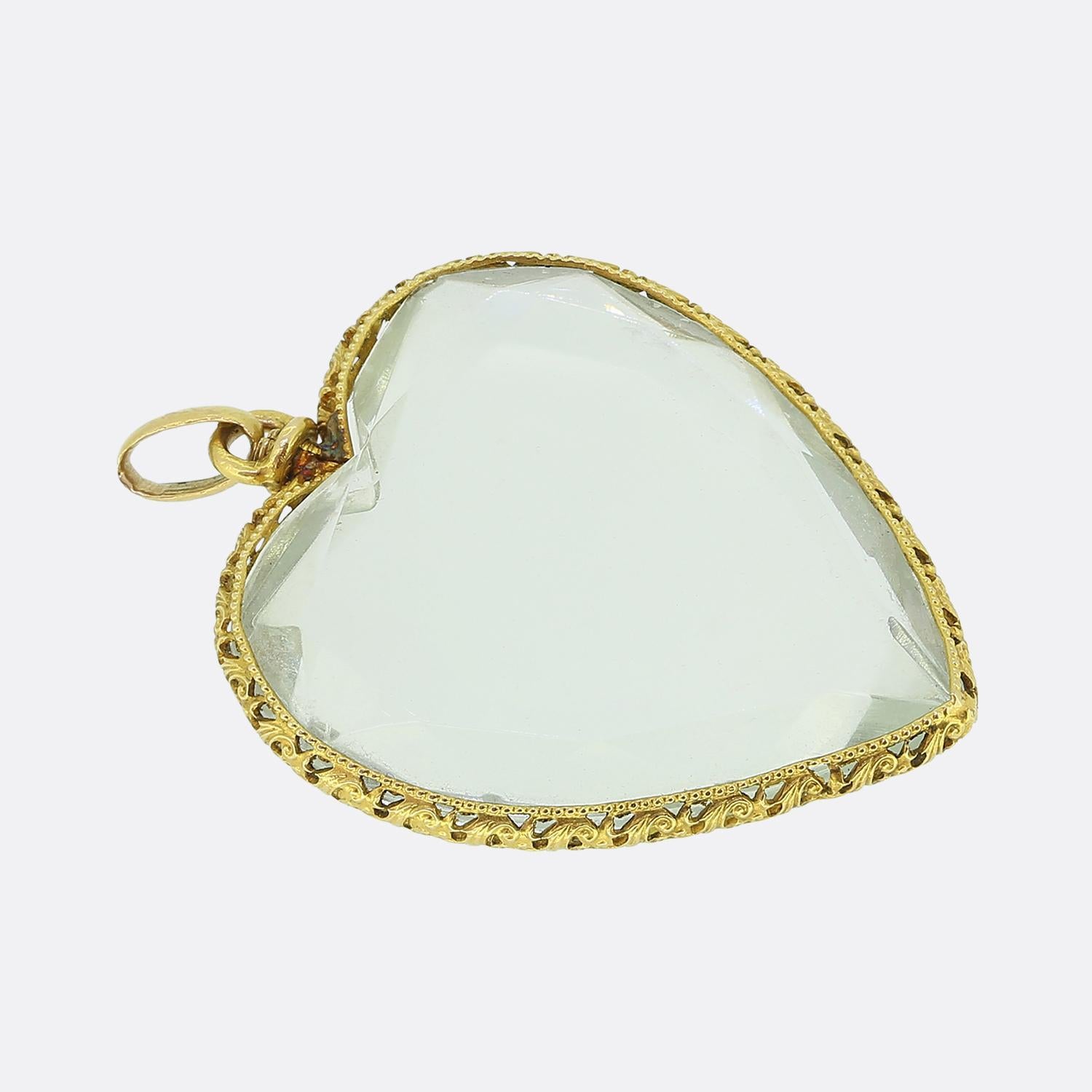 Voici un pendentif victorien en forme de cœur réalisé en or jaune 18ct. Ce pendentif romantique est orné d'un grand cristal de roche facetté d'une subtile teinte bleue, enchâssé dans une monture en or aux détails complexes. Le cadre présente un