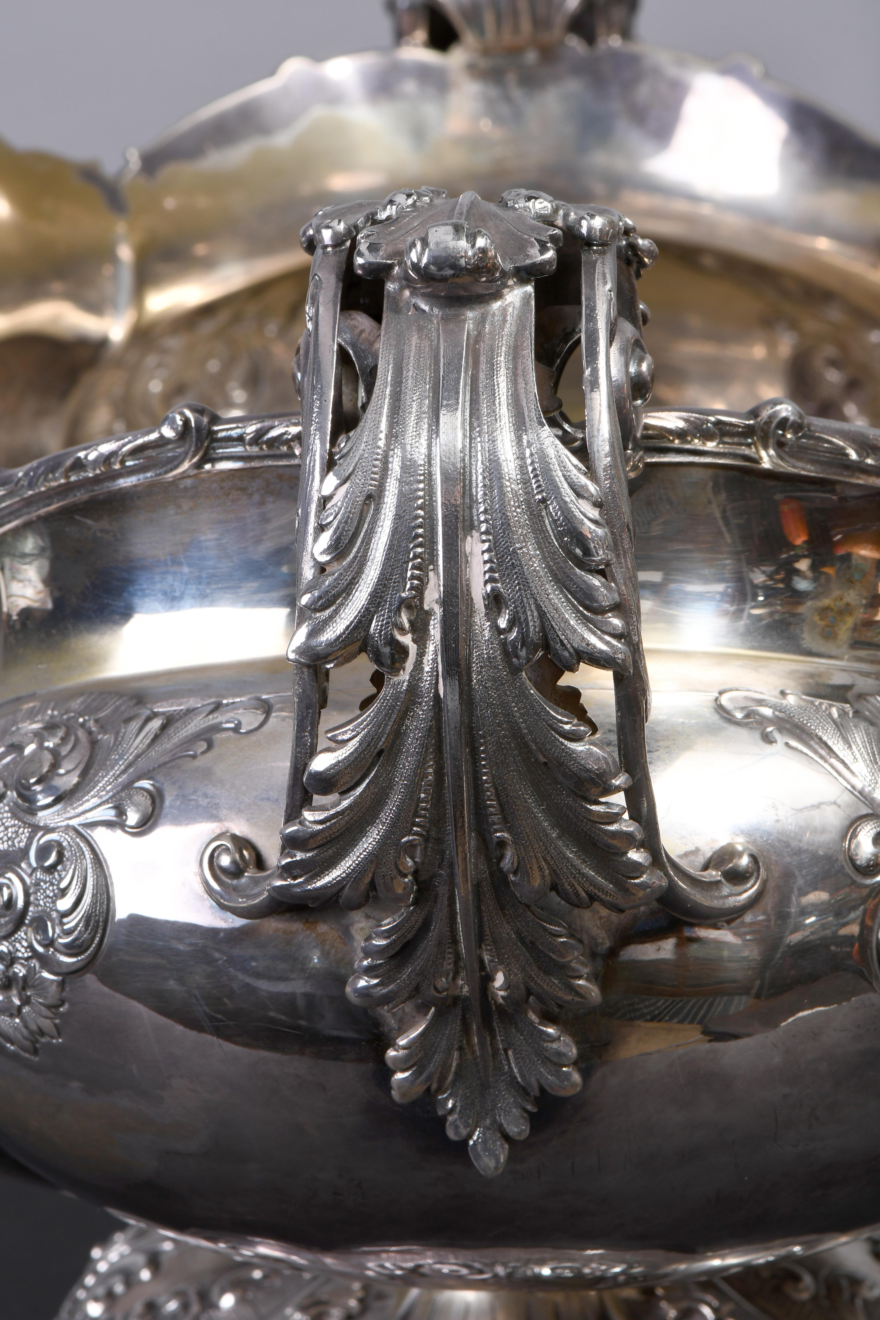 An ovoid fruit bowl having scrolls of acanthus leaves handles with arched molded shells and acanthus leaves rim. Its body is divided in eight ribbed bulb panels, each one adorn with 
repousse of flower leaves teardrop sconces, C-scrolls, and scroll
