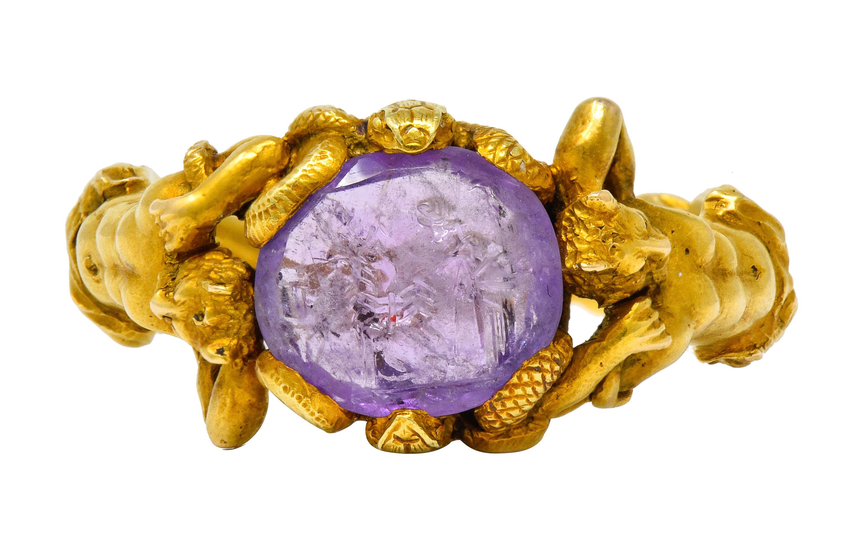 Centering an oval ancient carved amethyst intaglio measuring approximately 11.7 mm x 10.0 mm

Medium-light purple in color and carved to depict a figure with a donkey; Roman in origin

Set in place by winding snakes grappling with highly rendered