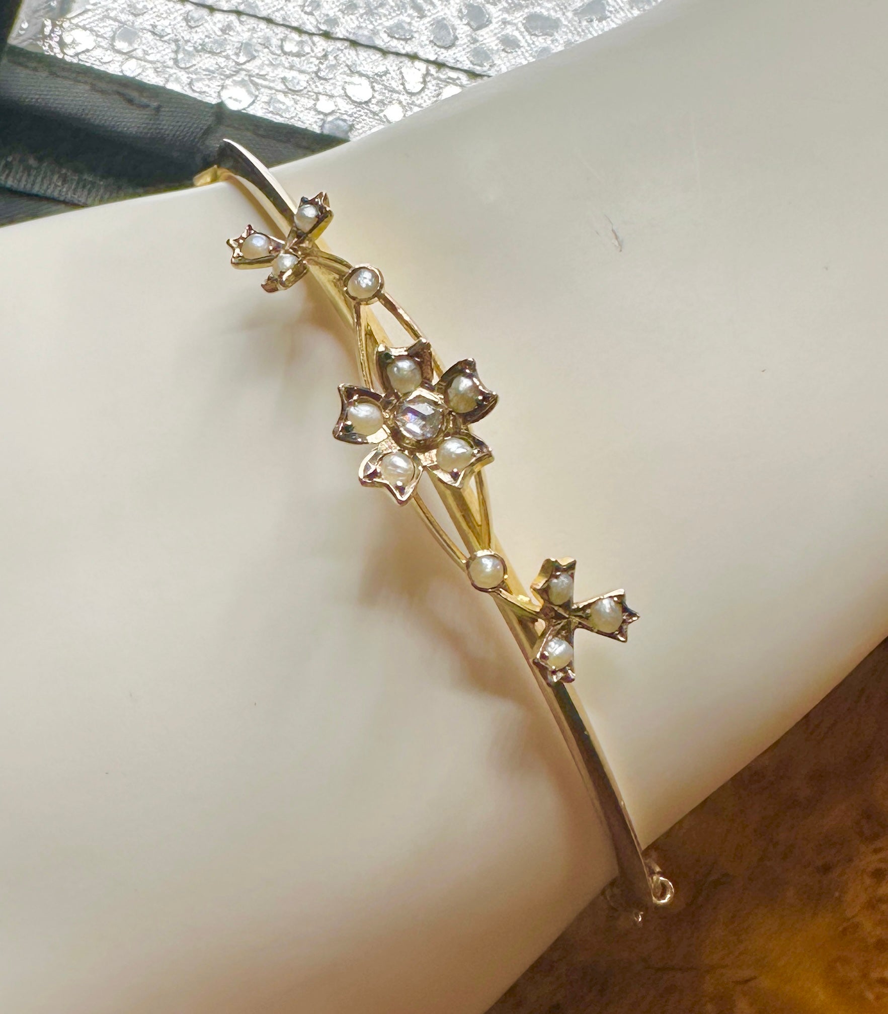 This is a delightful Victorian - Art Nouveau Bangle Bracelet with a Flower motif set with a central Rose Cut Diamond and Pearls in 10 Karat Gold.  The elegant flowers have a wonderful fully modeled three dimensional design.  The central flower has a