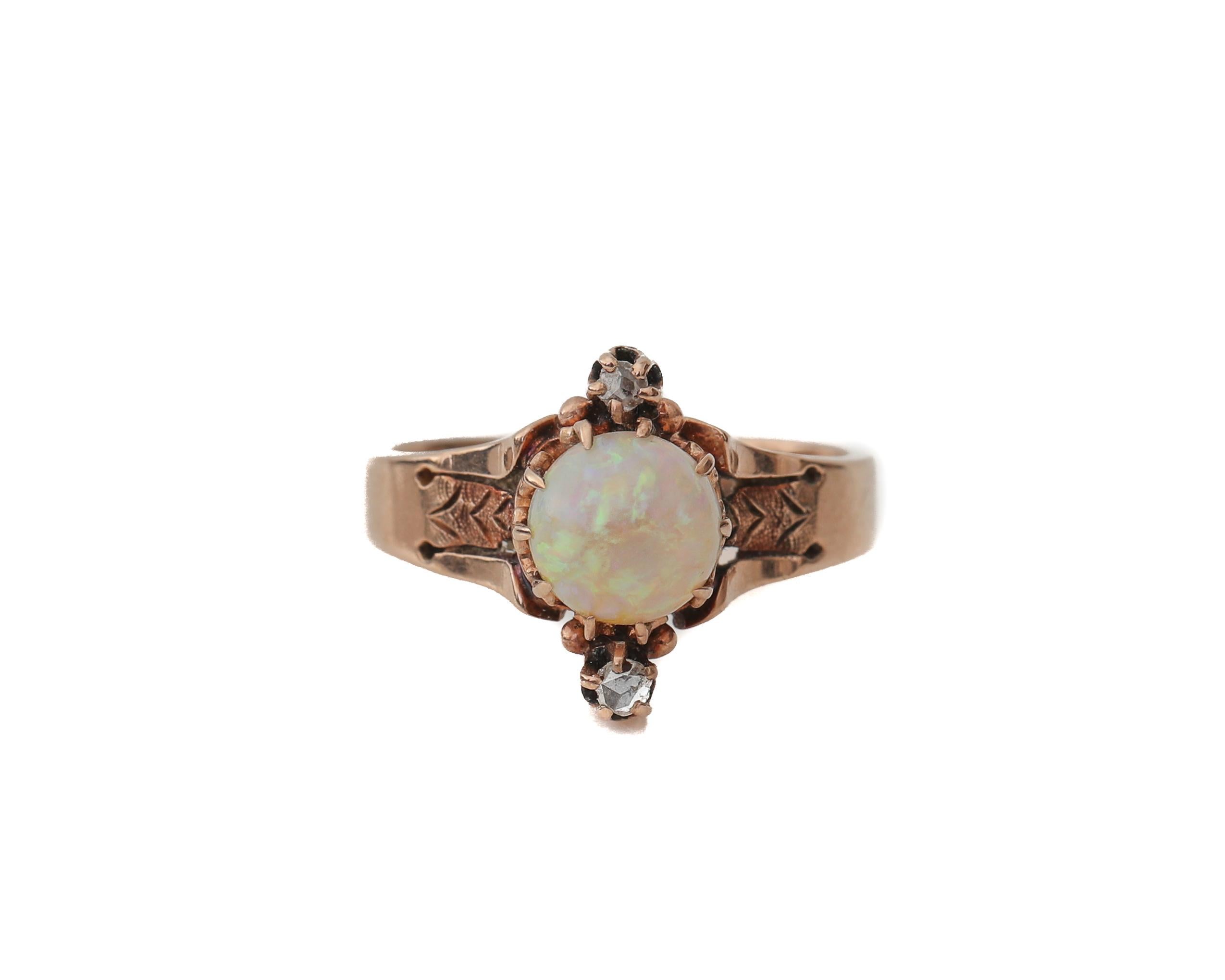 This genuine Victorian beauty is crafted of deep rosey 10k gold with a large center opal, flanked by diamond rose cuts. Talon prongs hold the opal cab and .02cttw accent diamond stones (2 total) in place. The raised etched design leading up to the