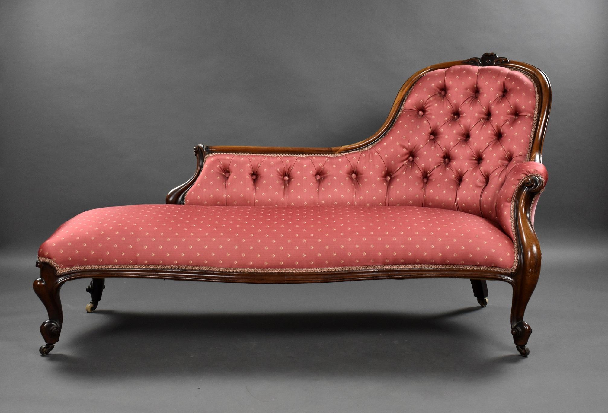 Victorian Rosewood chaise lounge in good condition with a shaped crest rail with floral carved pediment and scrolled terminals. The chaise has a buttoned back, upholstered in a patterned pale red silk, raised on scrolled cabriole supports
