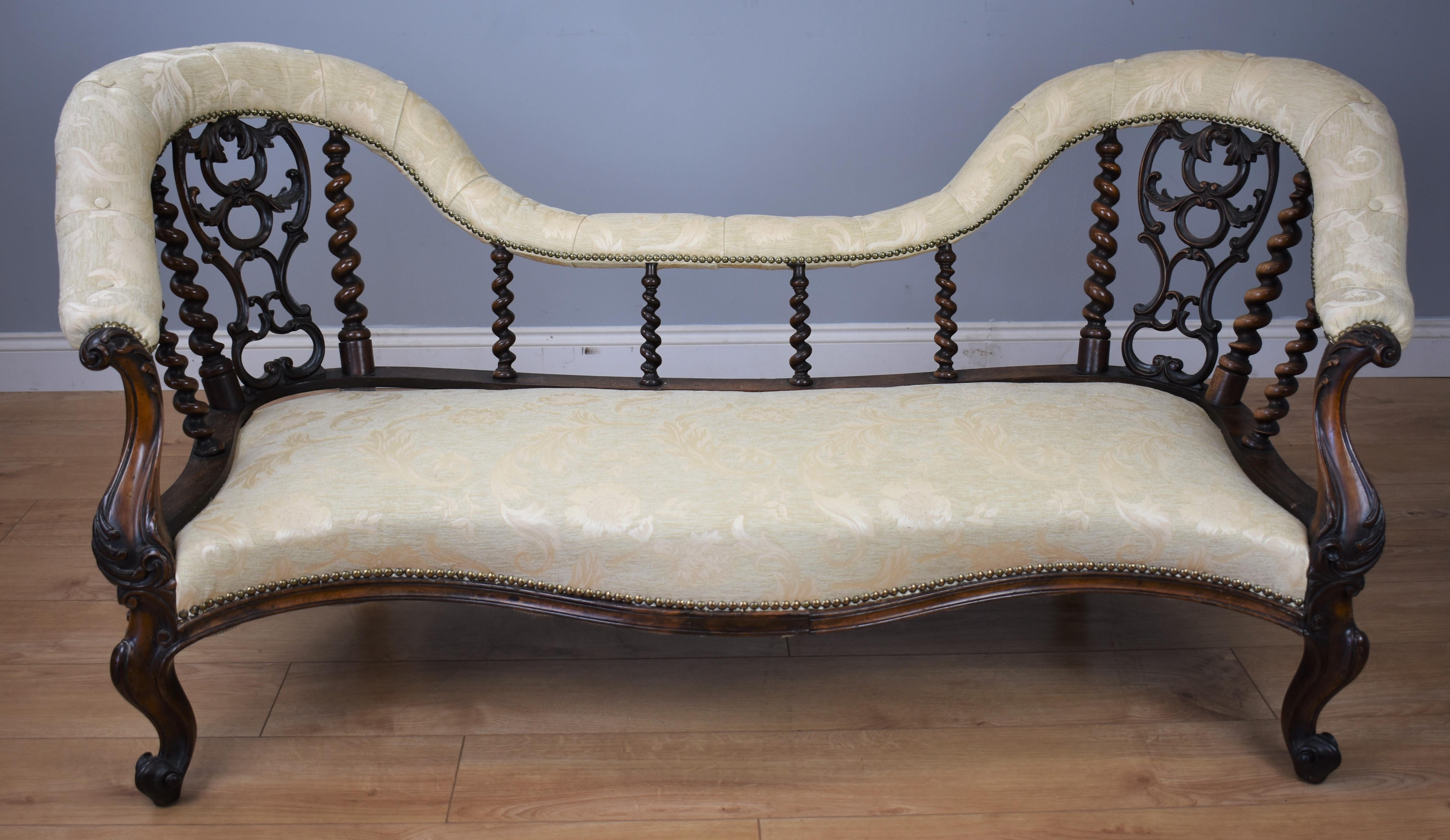 For sale is a Victorian rosewood chaise lounge in good condition having been recently upholstered and covered in a floral cream fabric with antique brass studs to the edge, the pair arched backs with pierced scrolling splats and barley twist