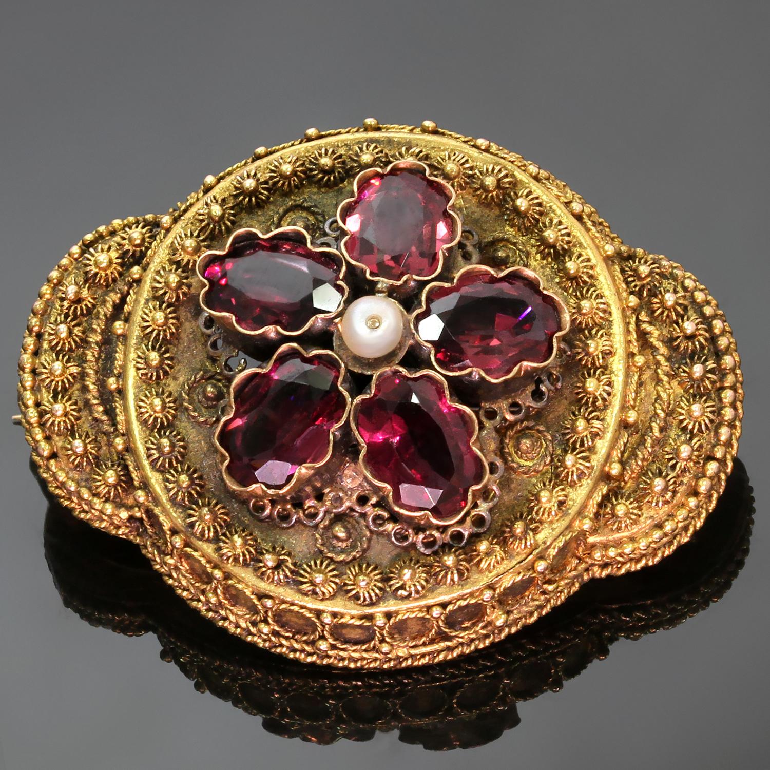 This rare antique Victorian brooch features an intricate filligree design hand-crafted in 15k yellow gold, set with faceted oval red rubillites, and completed with a saltwater natural pearl in the center. Brooch can also be worn as a pendant. Made