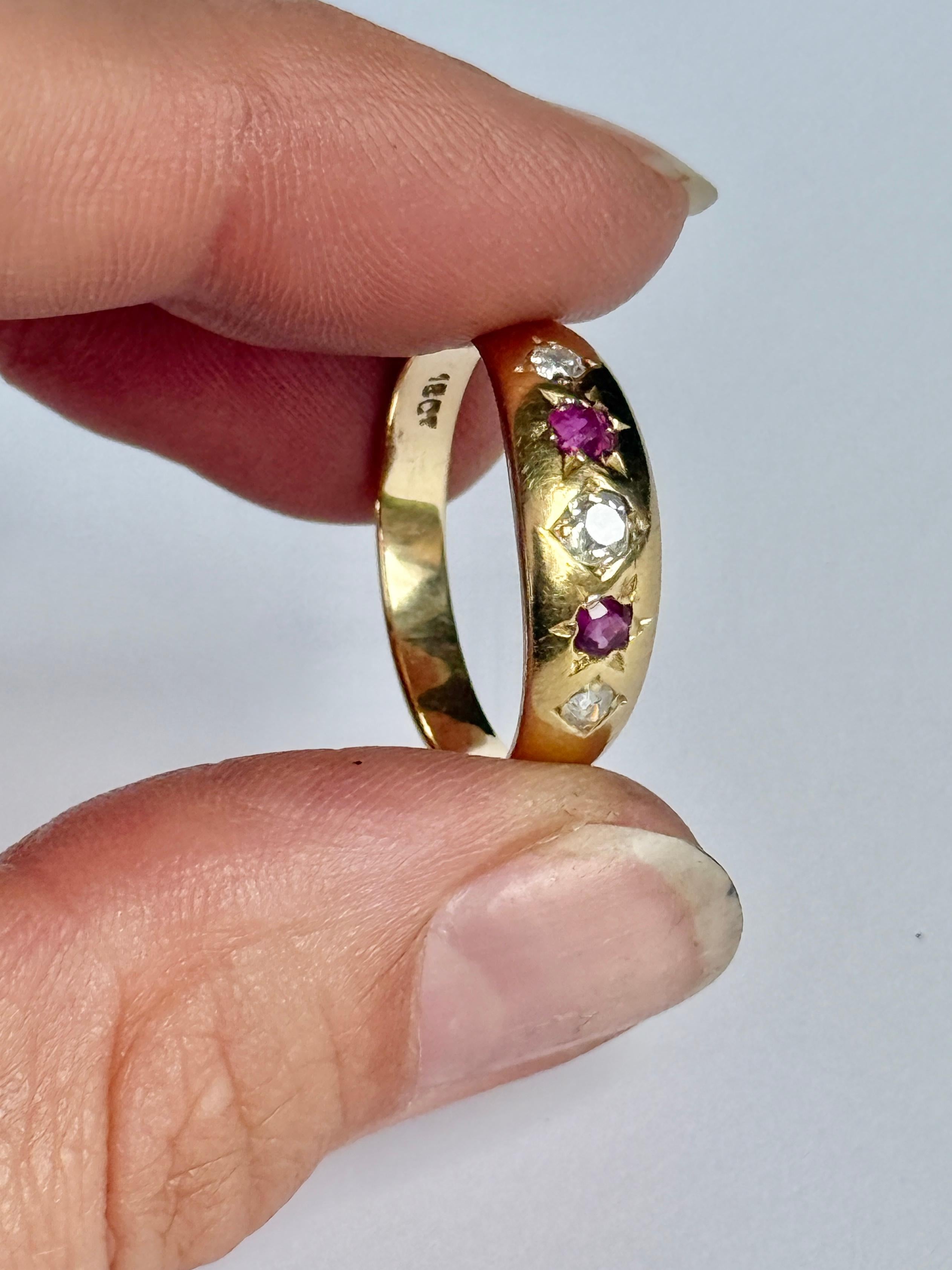The central diamond in this glossy 18ct gold band measures 15pts. The rubies and diamonds that sit either side of this stone measure 7pts each. 

Ring Size: Q or 8 
Band Width: 6.5mm 

Weight: 3.6g 