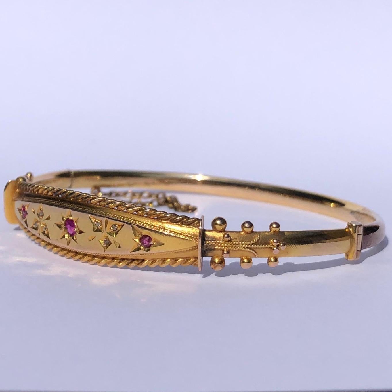 The 9 carat gold is bright the bangle has so much detail. The detailed panel holds rose cut diamonds set in pointed trefoils and rubies set in star settings. Either side of the decorative panel is rope twisted gold and the shoulders have orb