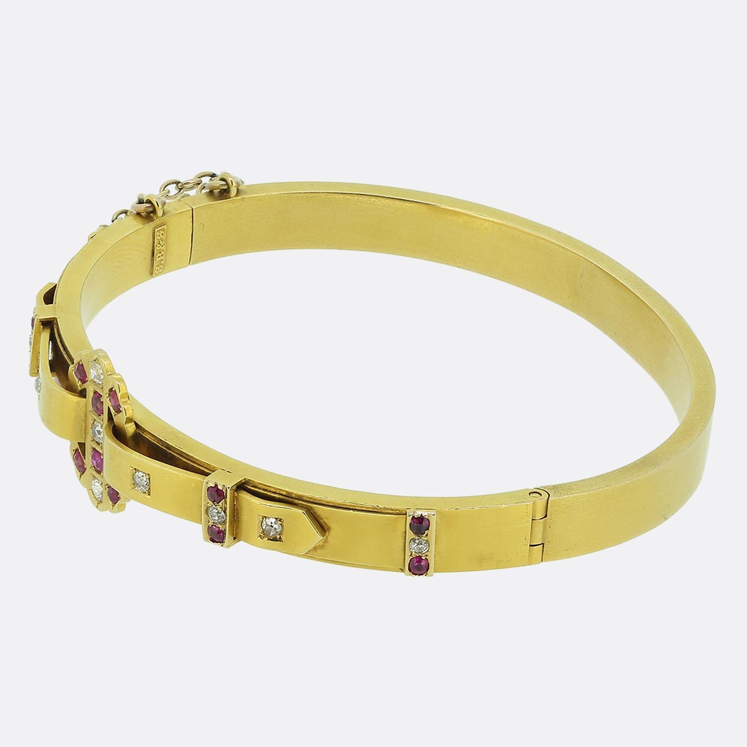 Here we have distinguished bangle crafted from a rich 18ct yellow gold during the Victorian period. This antique piece features a striking arrangement of red rubies, interspersed with old mine-cut diamonds that shimmer to showcase a bright white