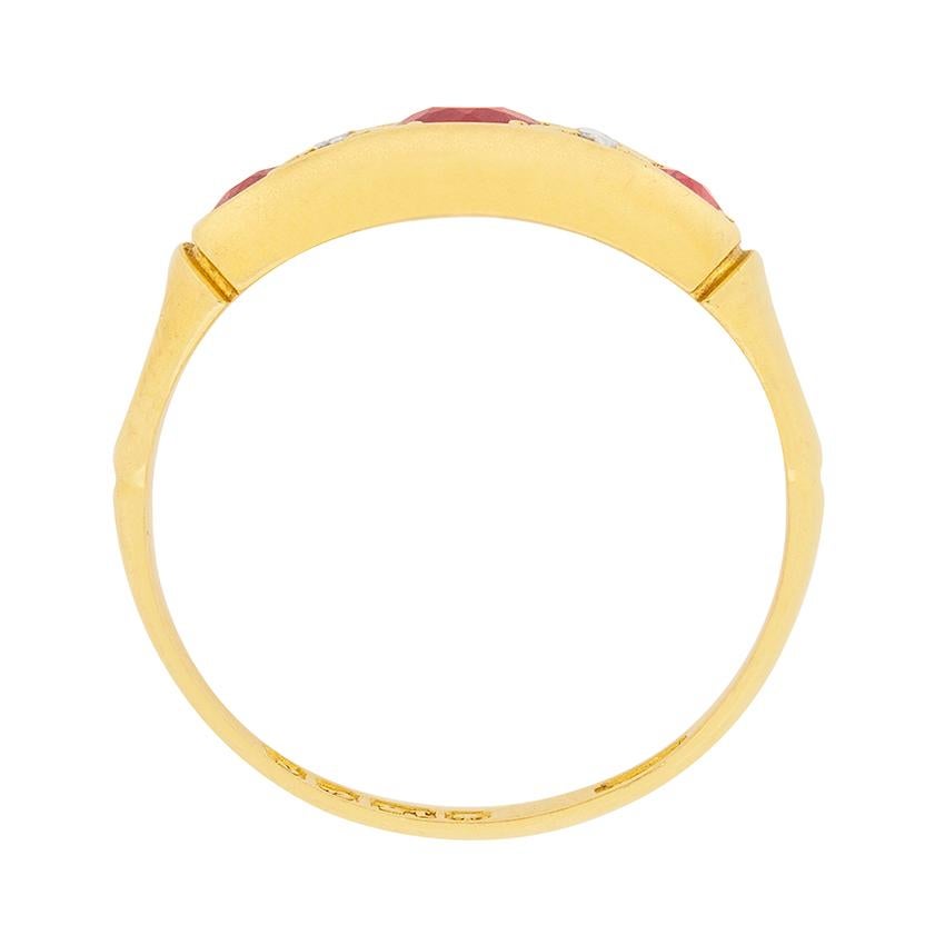 This delicate ring is hallmarked 1902 and is made in 18 carat yellow gold. It features a 0.35 carat ruby in the centre and two 0.15 carat rubies on either side. Surrounding the centre ruby are four rose cut diamonds each weighing 0.02 carat each.