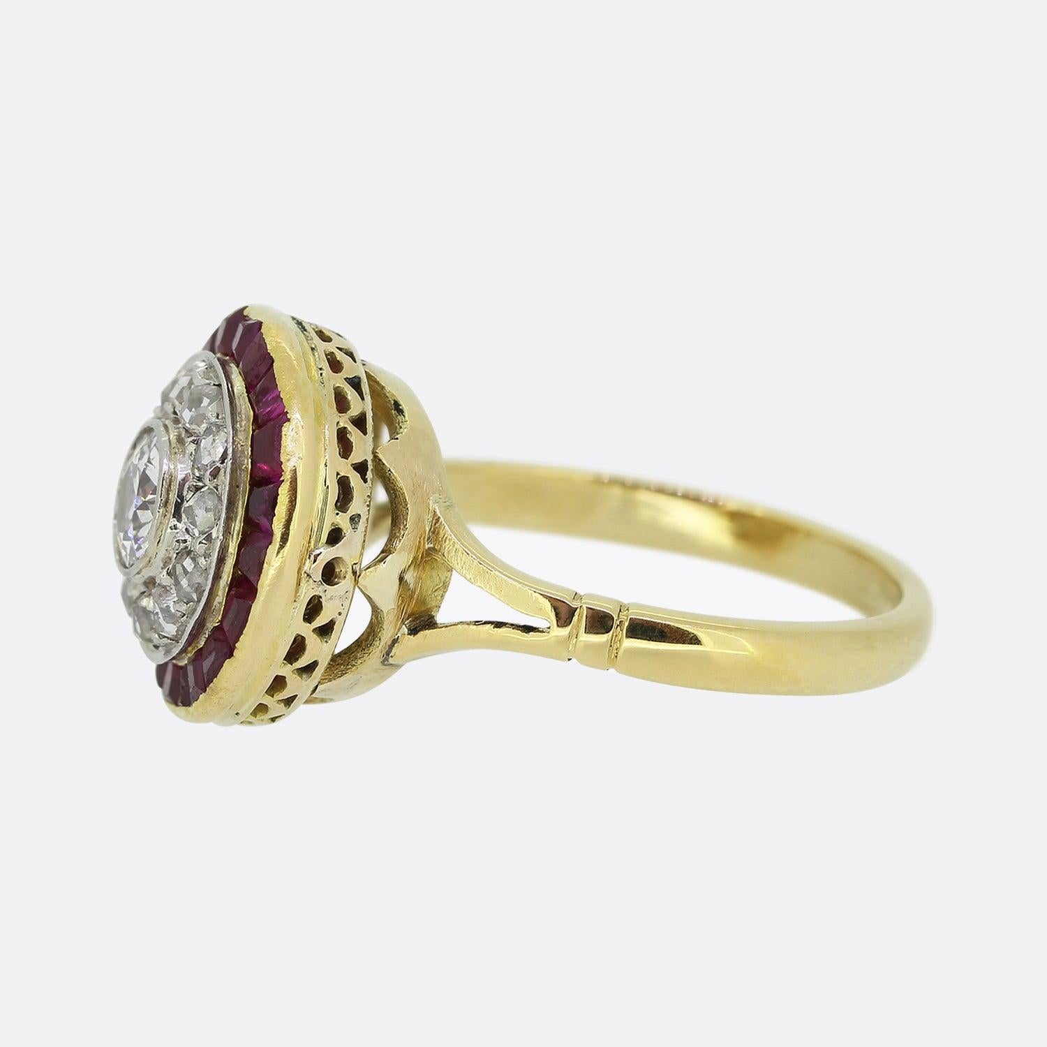 Here we have an 18ct yellow gold ruby and diamond cluster ring from the Victorian era. This multi-layered piece consists of a single round faceted old cut diamond at the centre which sits slightly risen in a rub-over setting. This principle stone is