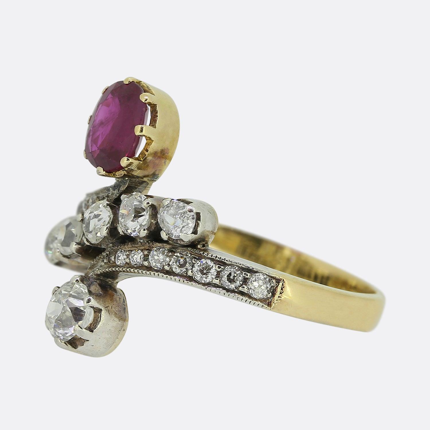 Here we have a charming ruby and diamond crossover ring from the Victorian era. This 18ct yellow gold piece focally showcases an oval shaped natural red ruby possessing a strong medium colour tone. At the bottom of the face we find an individually
