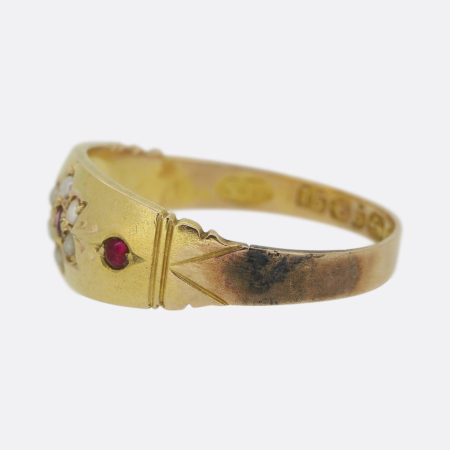 This is an antique 15ct yellow gold ruby and pearl ring from the Victorian era. The ring features a detailed sunflower motif at the front of the face adorned with seed pearls and a ruby at the centre which is flanked on either side by an additional