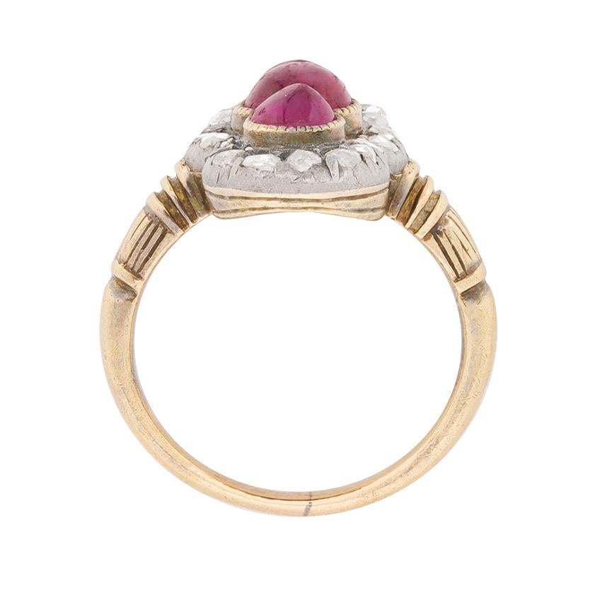 This quintessential Victorian era beauty features a vertically-arranged trio of rubies outlined by a grain set border of 0.24ct rose cut diamonds.

The gemstones, which feature a ruby cabochon at centre flanked by oval cuts, are set in platinum and