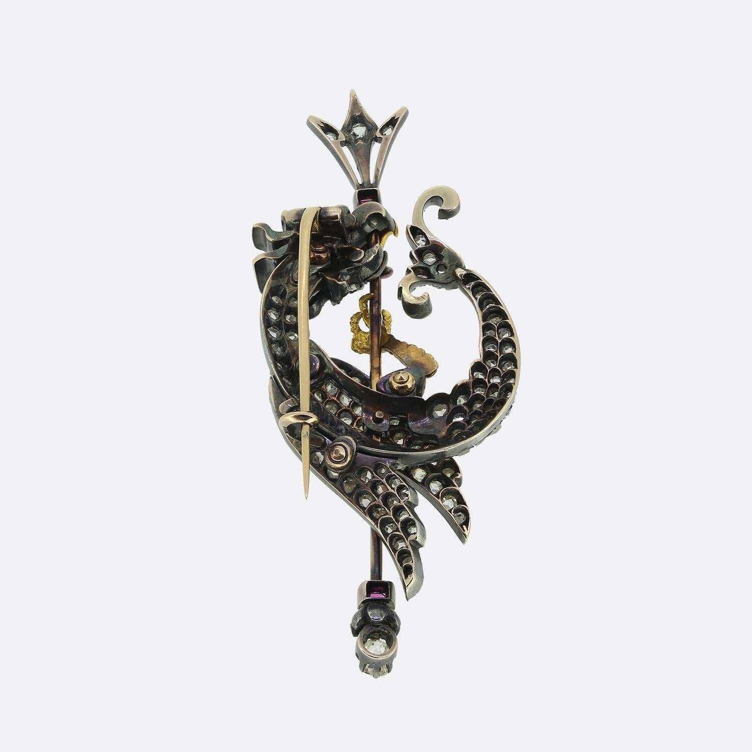 Here we have an exquisite Victorian brooch. This 19th-century piece showcases a striking cockatrice motif, meticulously crafted with a combination of gold and silver. The cockatrice's face, body, neck, wings and tail have been adorned with a