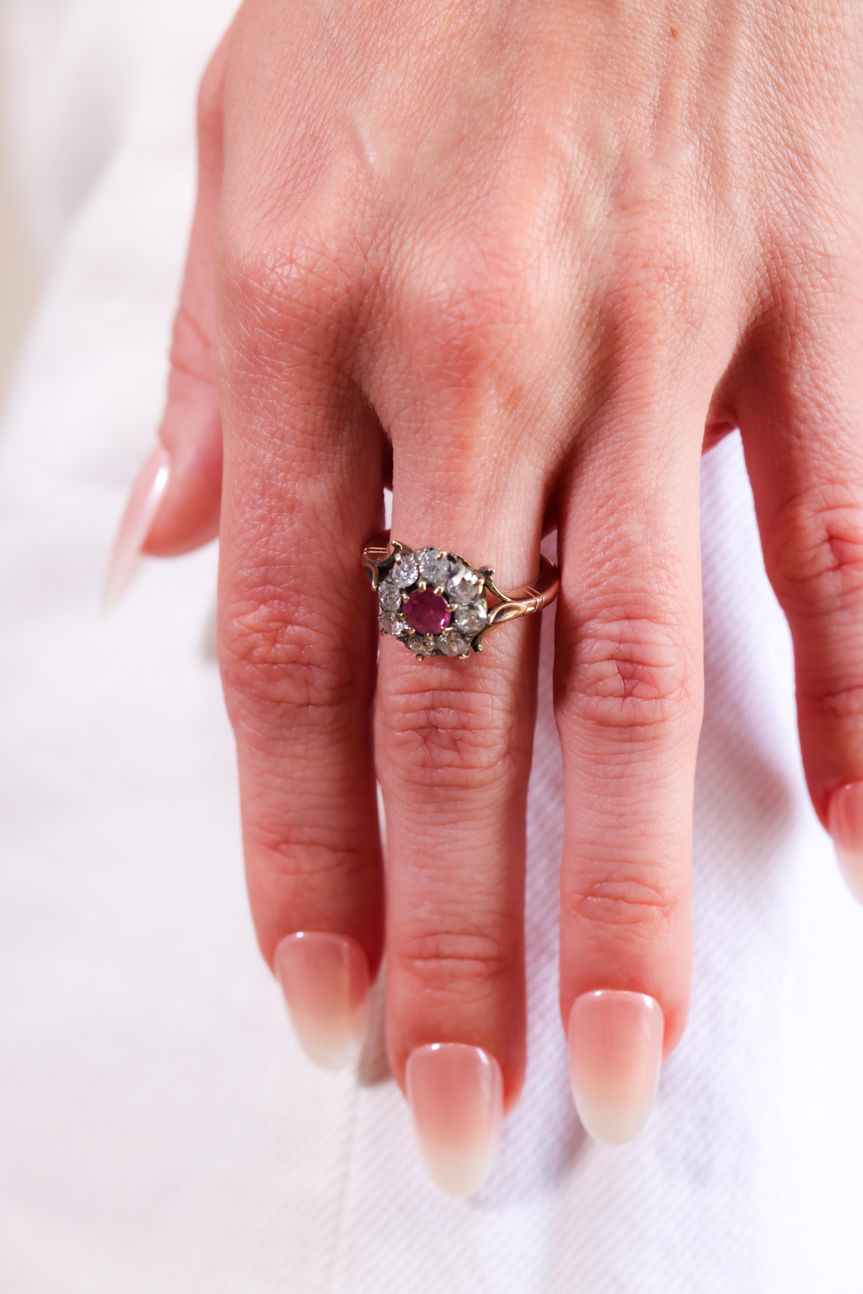 A spectacular and authentic Victorian era (circa 1890) yellow gold ruby and diamond halo ring. The Round Mixed Cut center ruby is a stunning pinkish-red hue and is gauged at approximately 0.55 carat. Further decorated with a halo of eight Old Mine