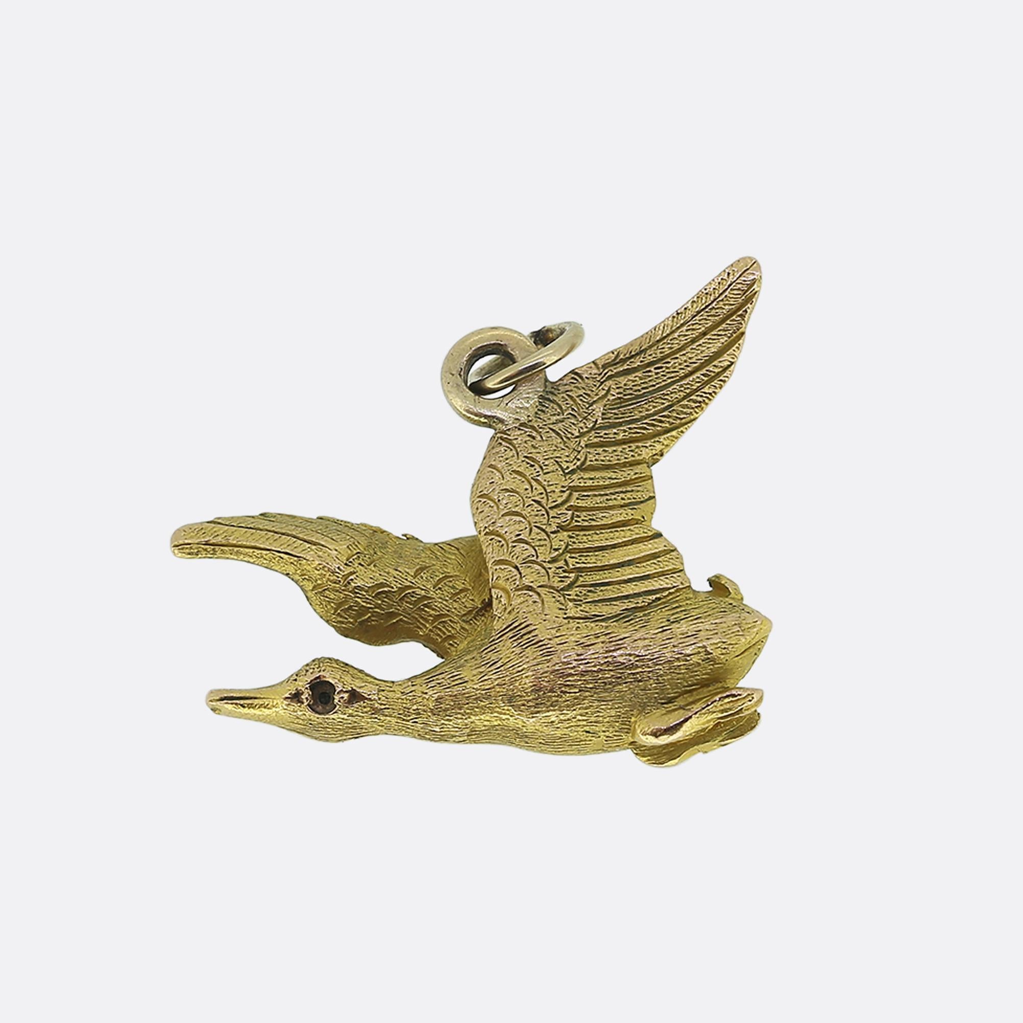 Here we have a 9ct yellow gold charm, crafted into the form of a flying duck. The charm features intricate detailing on the wings and body, capturing the essence of motion. A single red ruby serves as the bird's eye on either side, adding a touch of