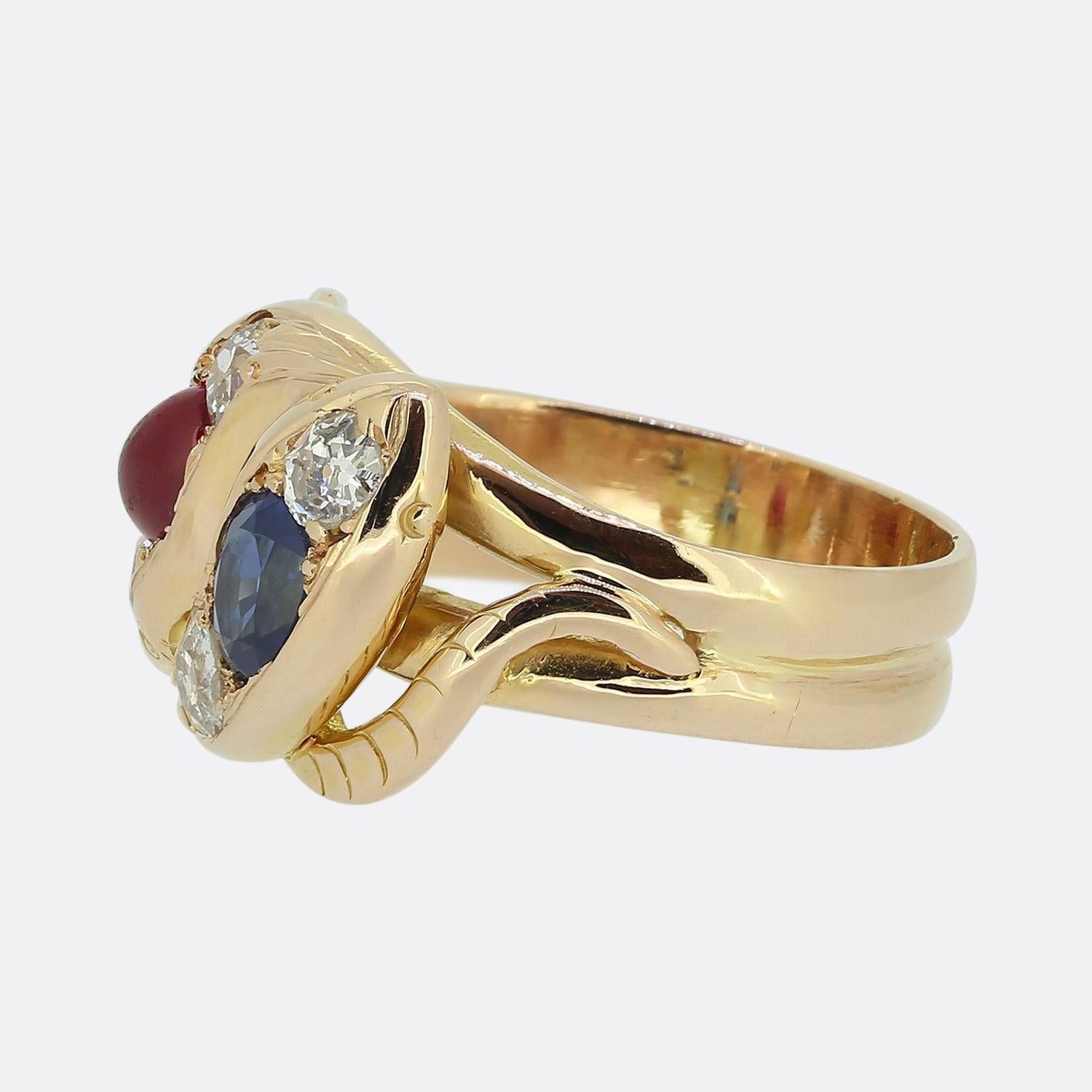 Here we have a stunning double snake ring dating back to the Victorian period. Crafted from 18ct rose gold, this ring features two snake heads, one of which is set with an oval faceted medium-blue sapphire whilst the other is set with a round