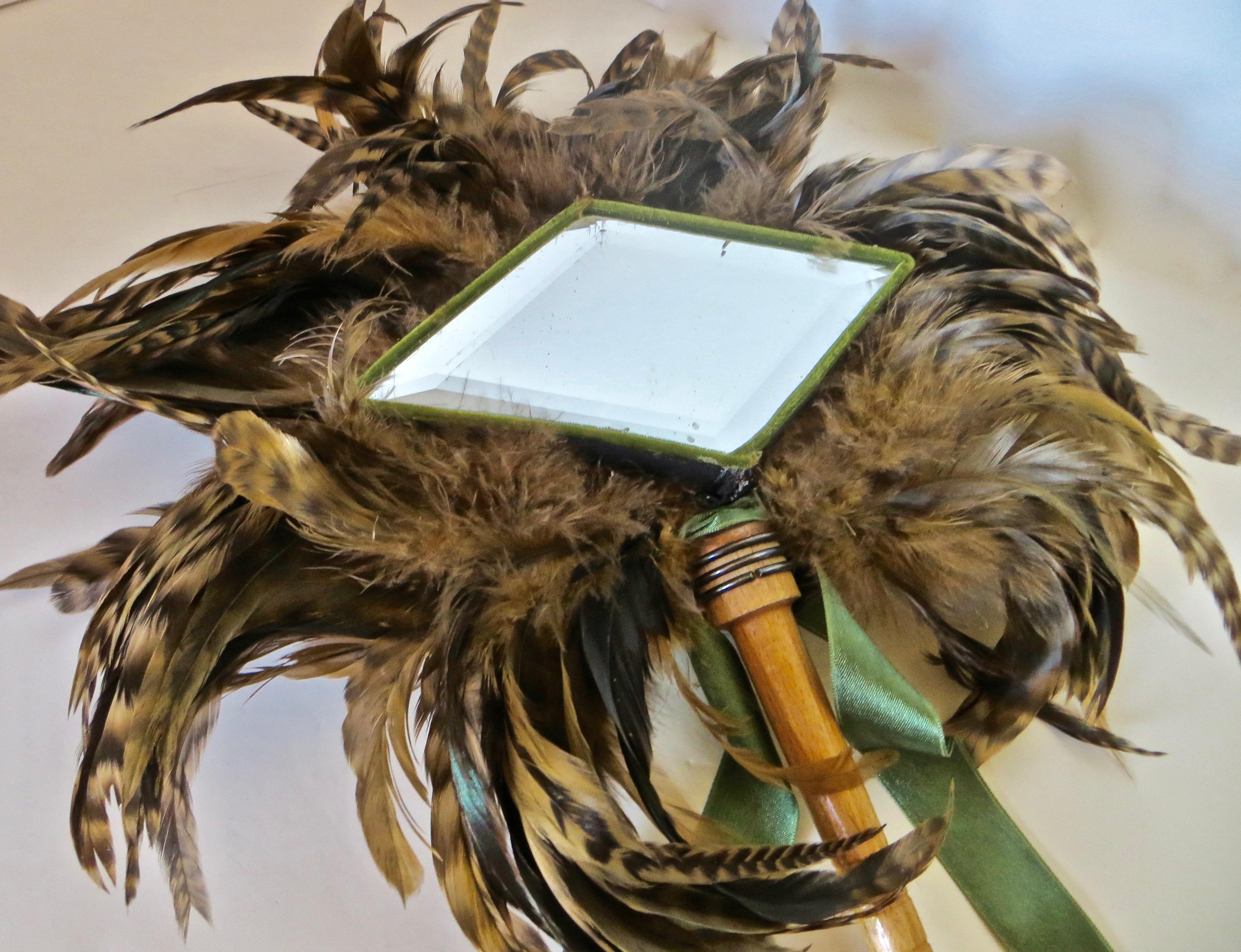 Very unique one of a kind item, this is a hand held Victorian mirror, very fancy with pheasant wing feathers galore and a green satin ribbon 