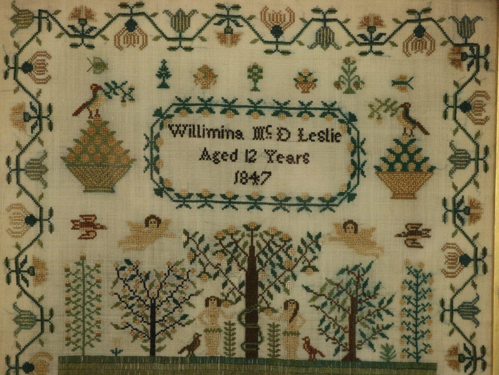 1847 Victorian period Sampler by Willimina McD Leslie Aged 12. The sampler is worked in silk on linen ground, in a variety of stitches. Meandering floral border. Colours green, light brown, dark brown, gold and silver. Signed and dated 'Willimina