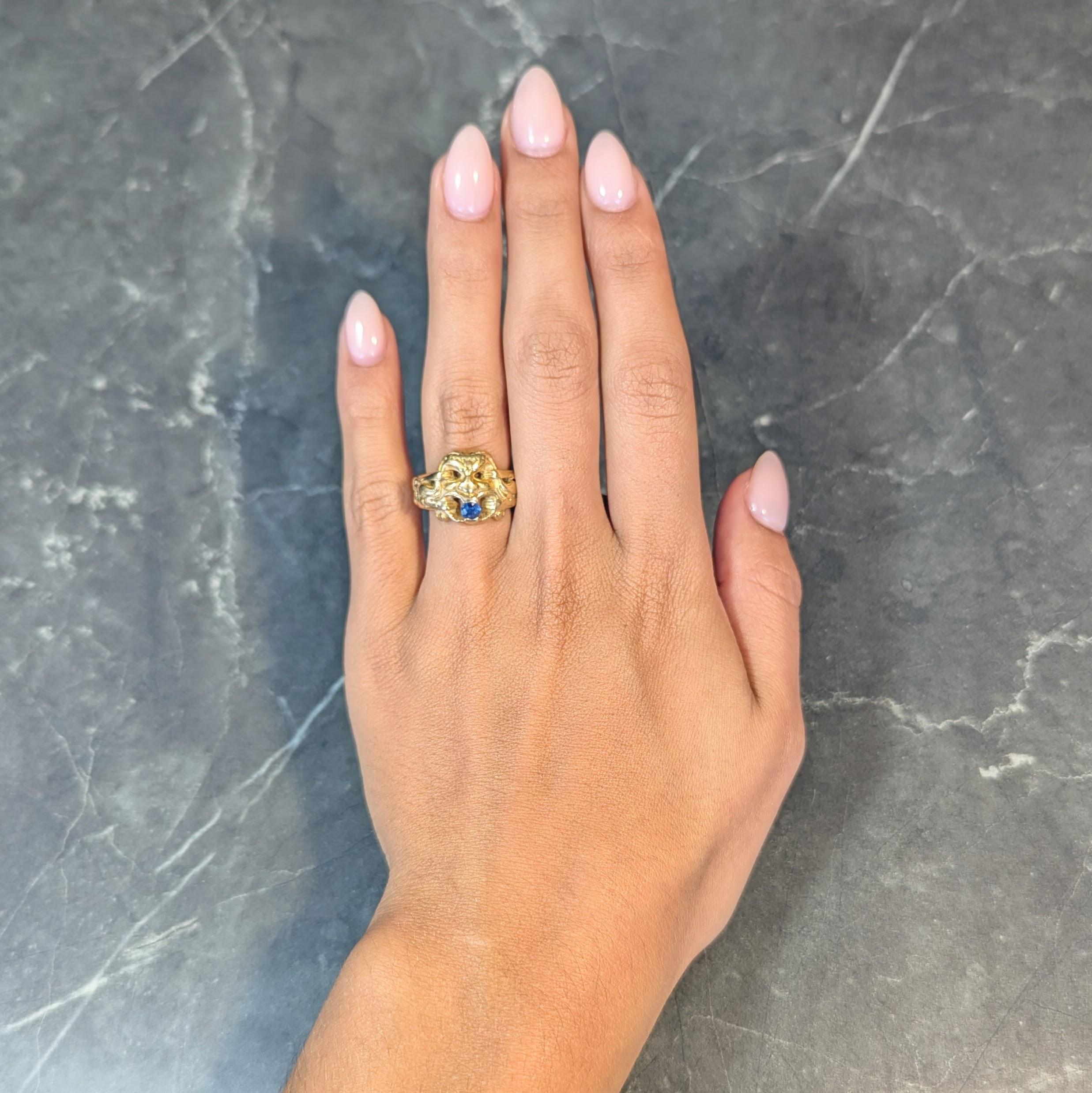 Designed as a stylized God Of Wind mask with grooved features
Pierced with open mouth and wind trailing out to form band 
With furrowed brow and braided headband 
Holding a round cut sapphire in its mouth
Weighing approximately 0.25 carat
