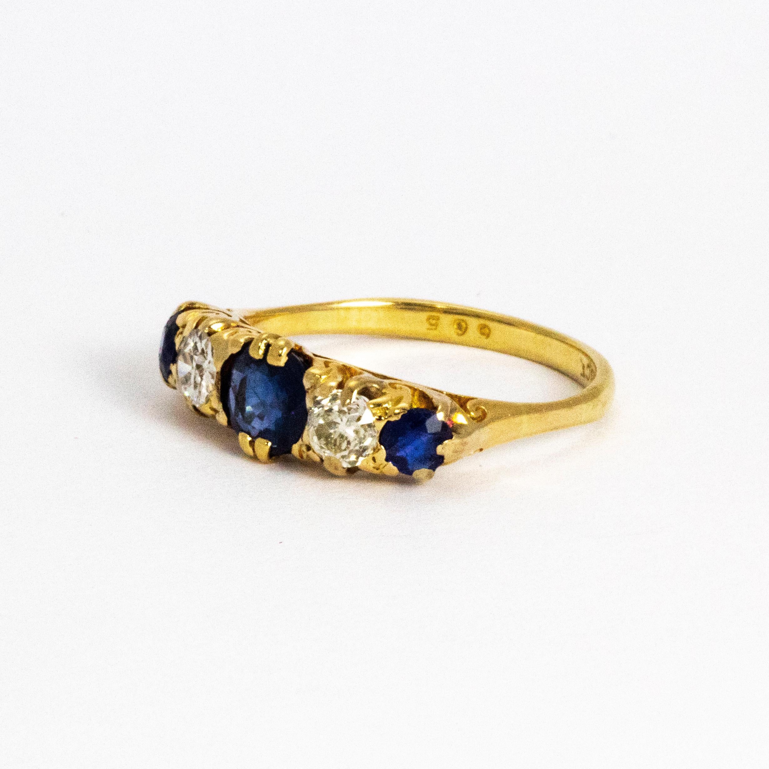 This sparkling ring boasts a beautiful blue sapphire central stone measuring approximately 65pts, two old cuts diamonds either side measuring approximately 20pts each and two smaller sapphires on the outer edge. The setting has beautiful scroll