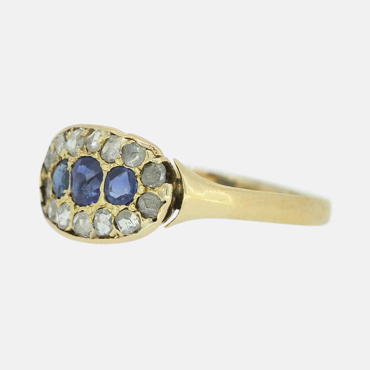 Here we have an 18ct yellow gold cluster ring from the Victorian era. The ring is set with an oval shaped sapphire to the centre which is flanked on either side by a single round shaped sapphire. These focal gemstones are then accentuated by a