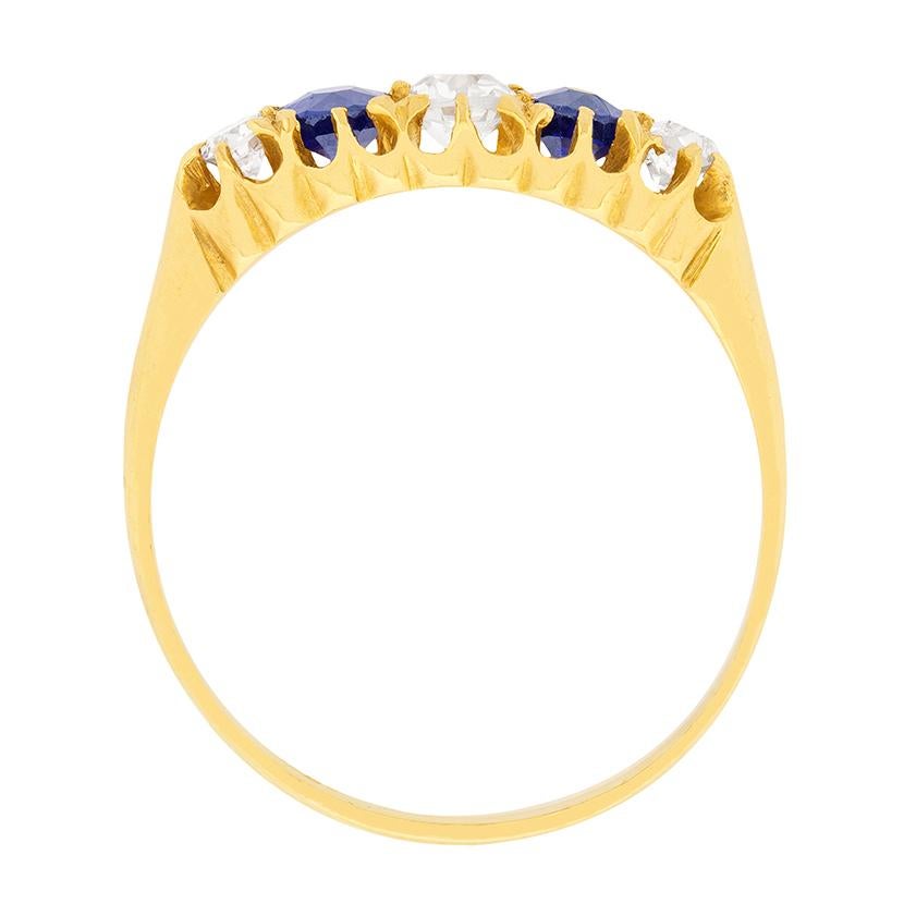 This Victorian era five stone ring was handmade in 18 carat yellow gold around 1890. The ring centres an old cut diamond between two similarly-sized, oval-shaped natural royal blue sapphires which total to 0.40 carats, and a slightly smaller diamond