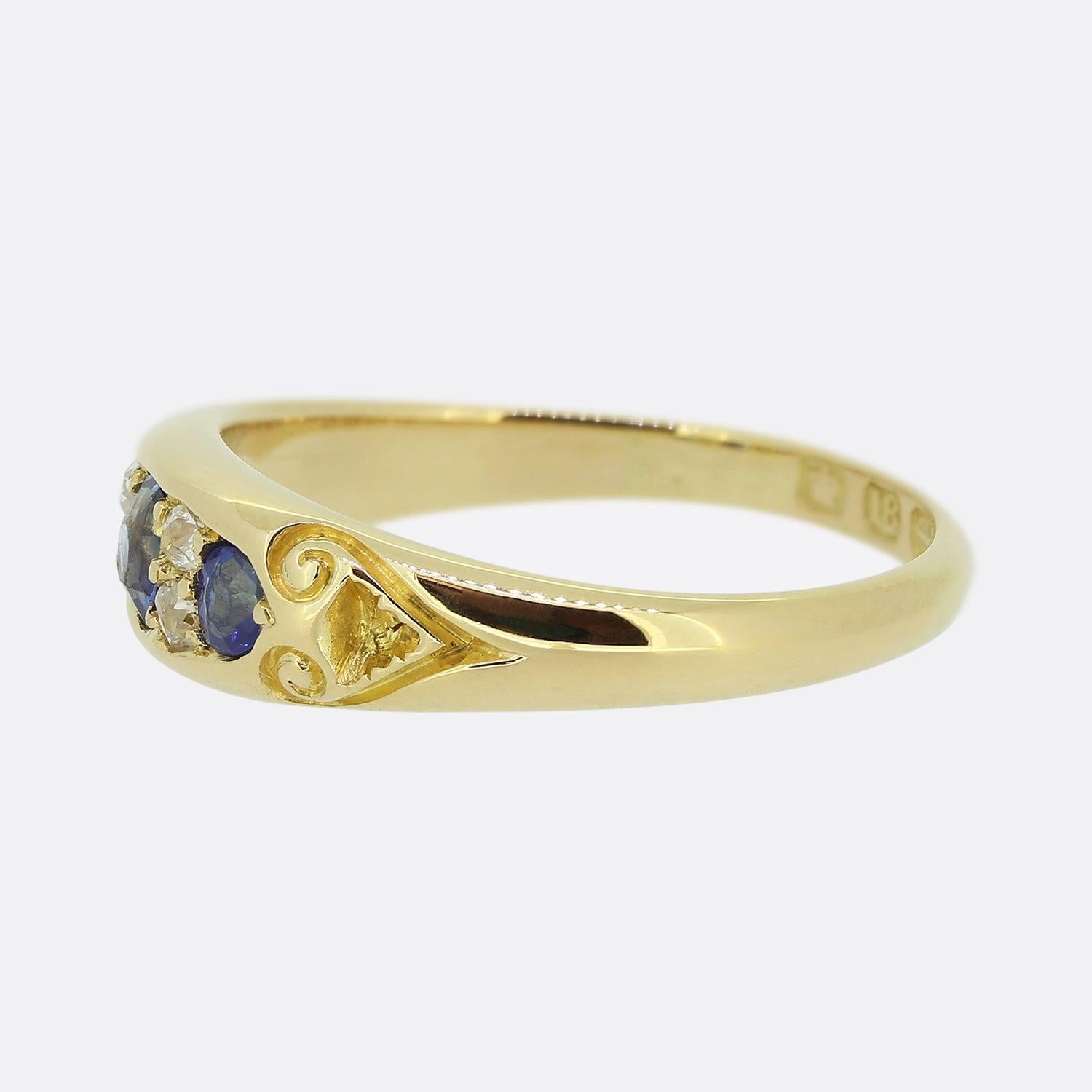 This is an antique sapphire and diamond ring from the Victorian era. An 18ct yellow gold mount plays host to three oval shaped sapphires possessing a wonderfully rich blue hue. These focal stones are individually separated by a duo of round faceted