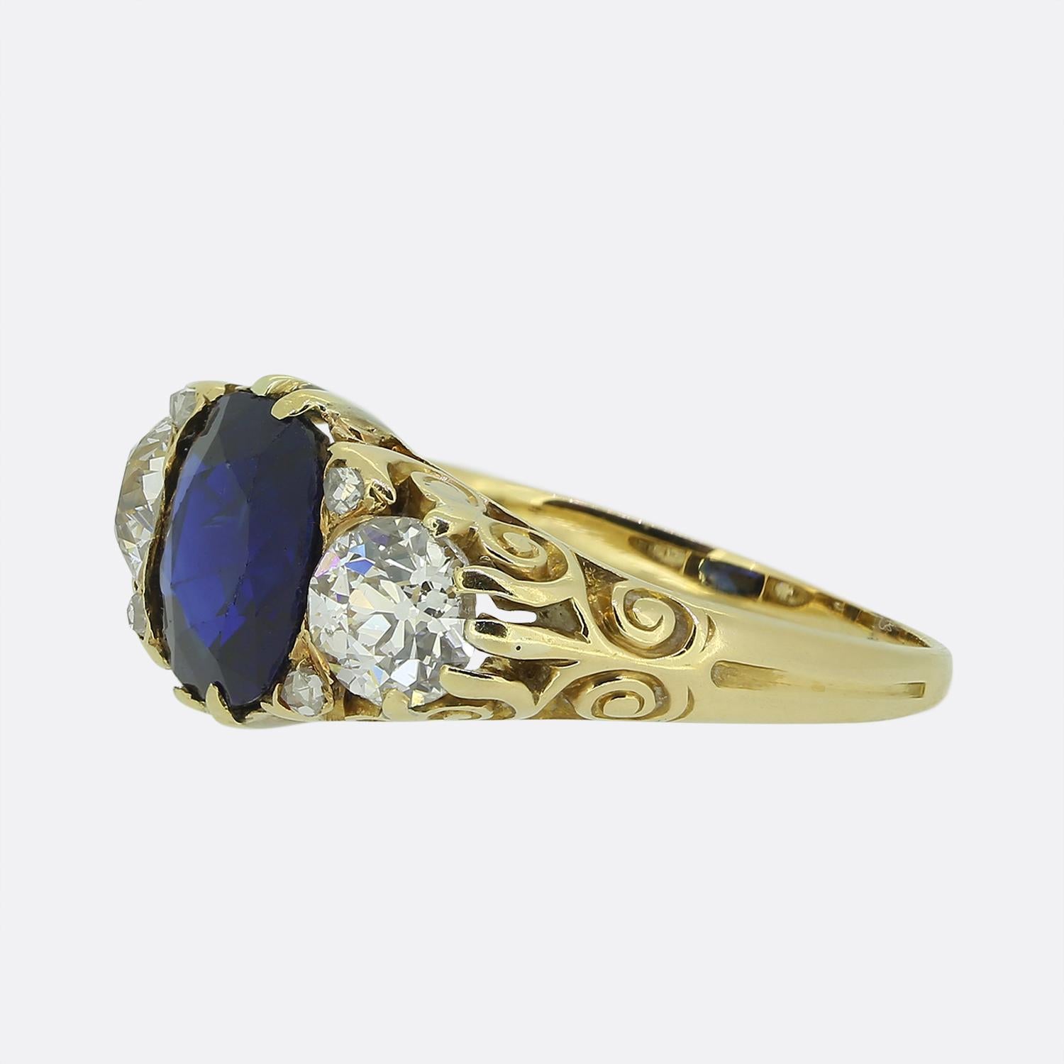 Nous avons ici une magnifique bague à trois pierres datant de l'époque victorienne. Au centre du visage se trouve un saphir bleu rond et facetté, d'une teinte profonde et captivante. Le saphir est flanqué de part et d'autre d'un diamant rond à